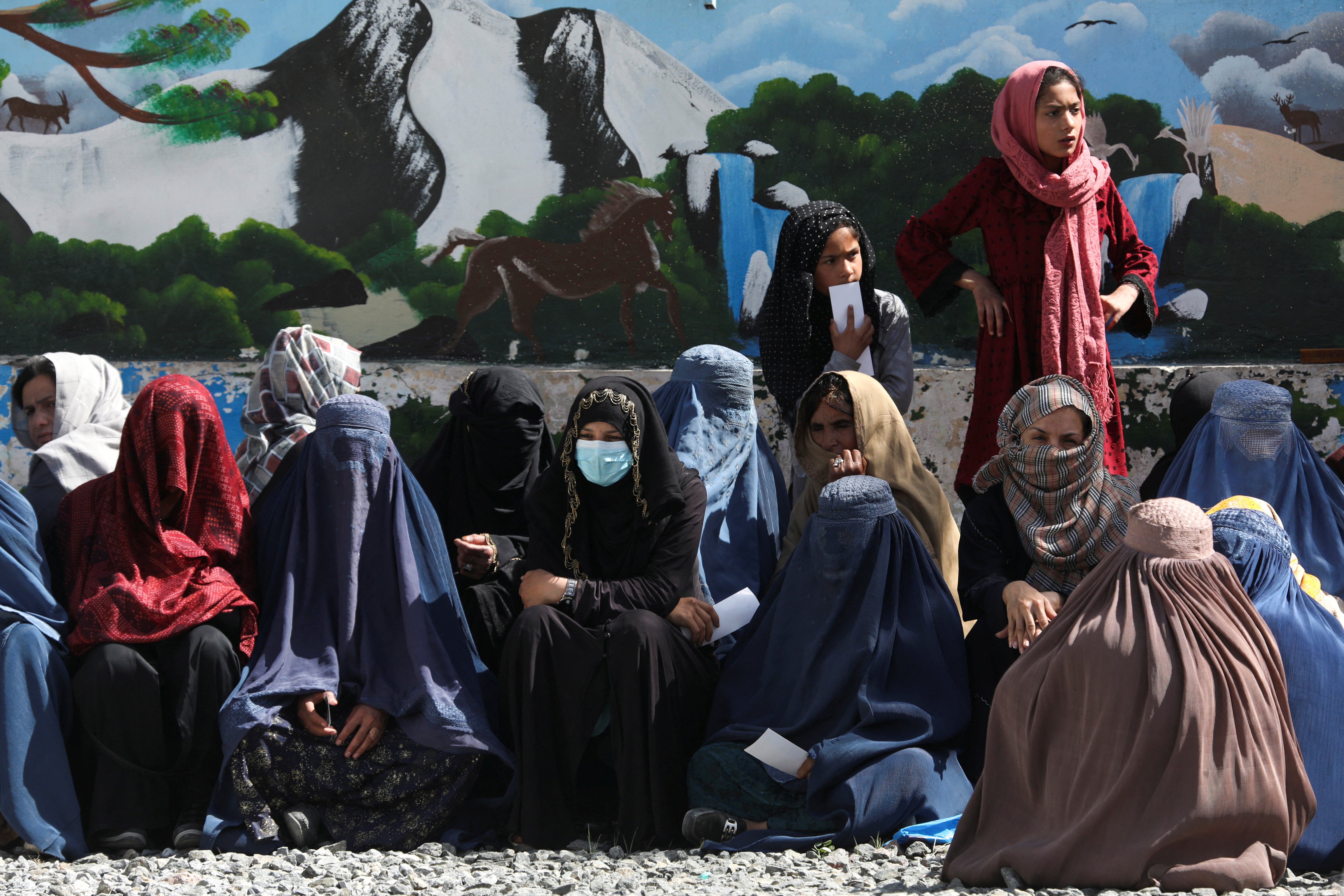 Afghan women wait to receive food packages distributed by a Saudi Arabian humanitarian aid group at a distribution centre in Kabul