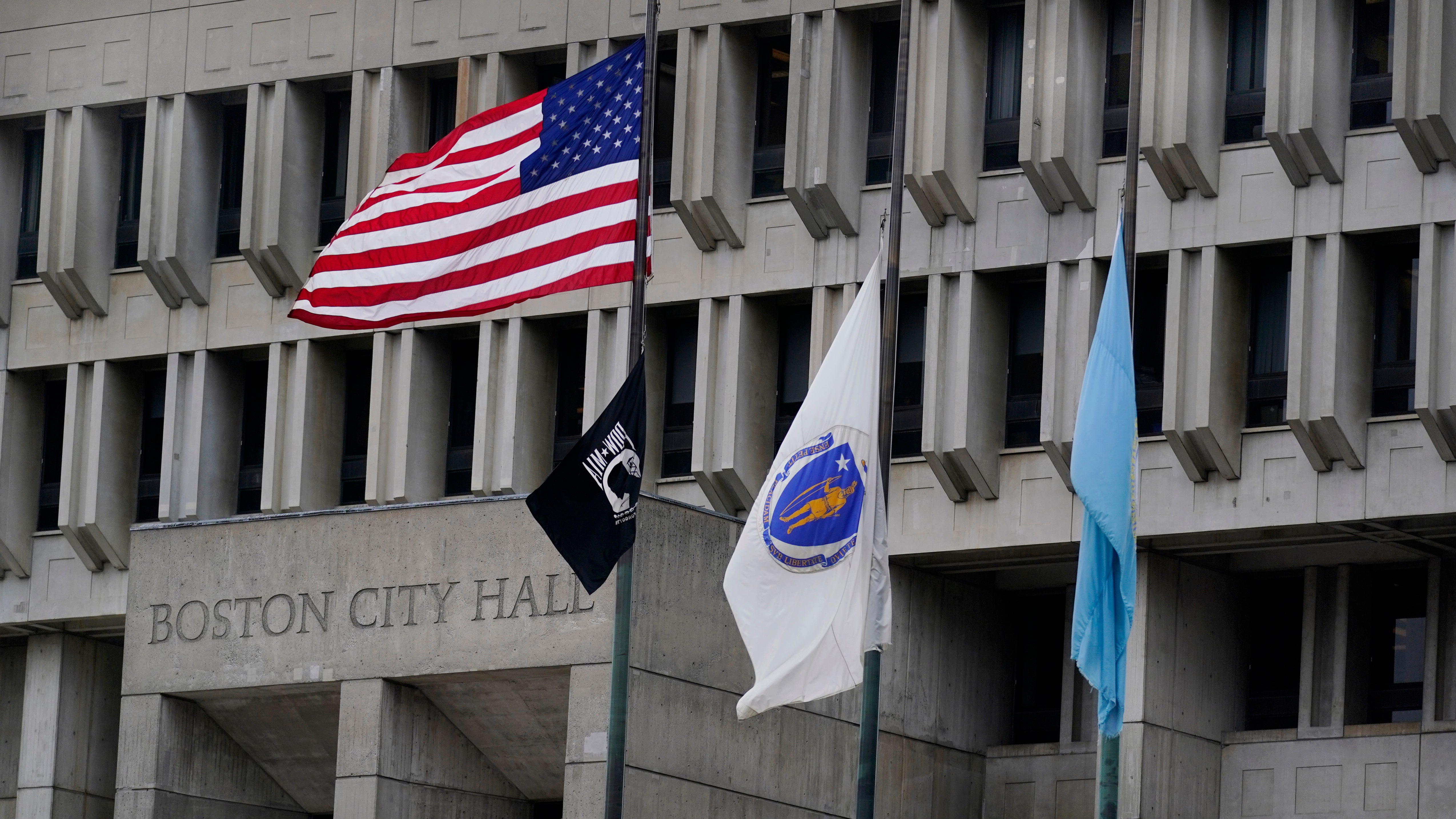 The American flag, the Commonwealth of Massachusetts flag, and the City of Boston flag, from left, fly outside Boston City Hall, Monday, May 2, 2022, in Boston.