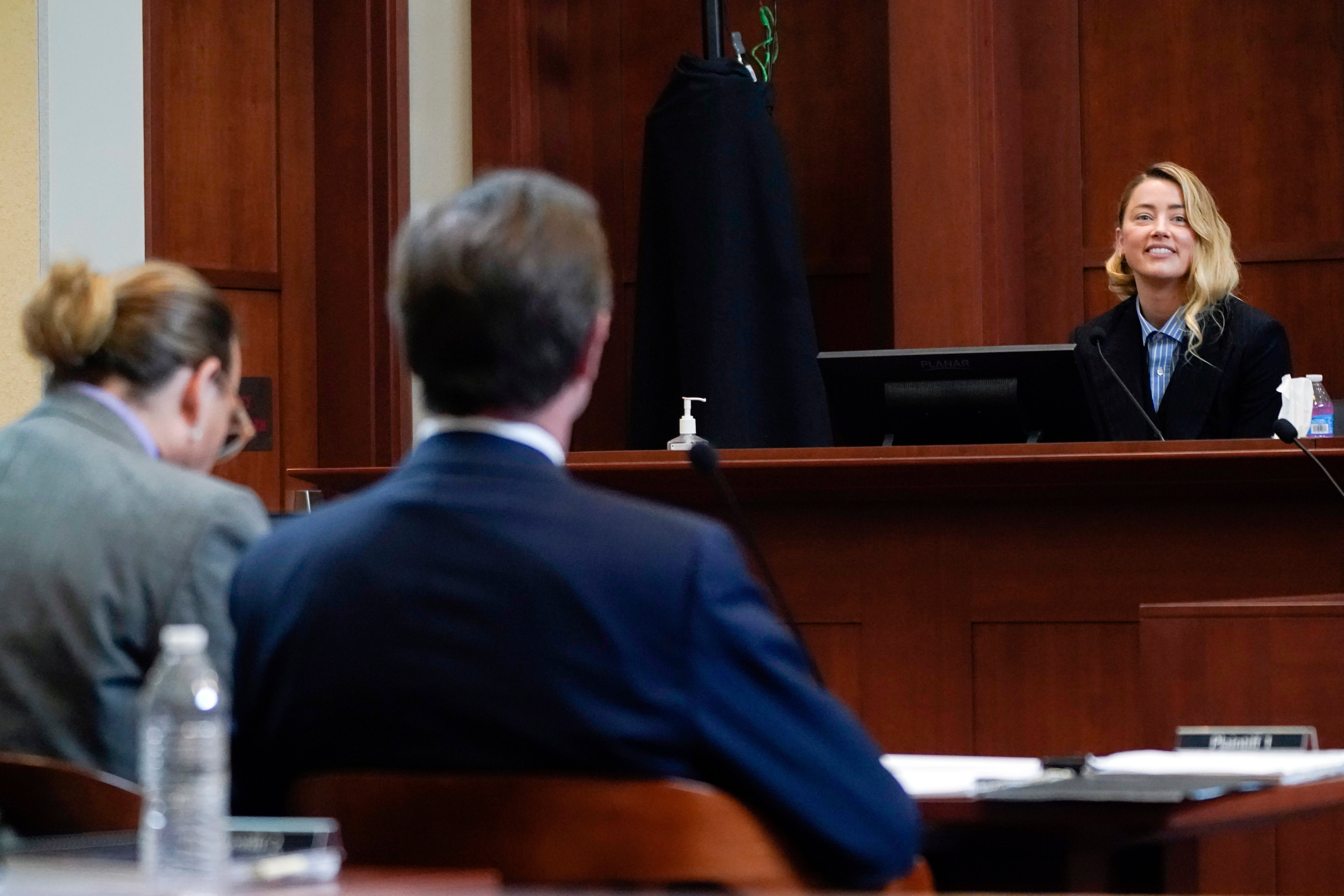 Actor Amber Heard testifies in the courtroom as actor Johnny Depp, left, listens at the Fairfax County Circuit Court in Fairfax, Va., Wednesday May 4, 2022