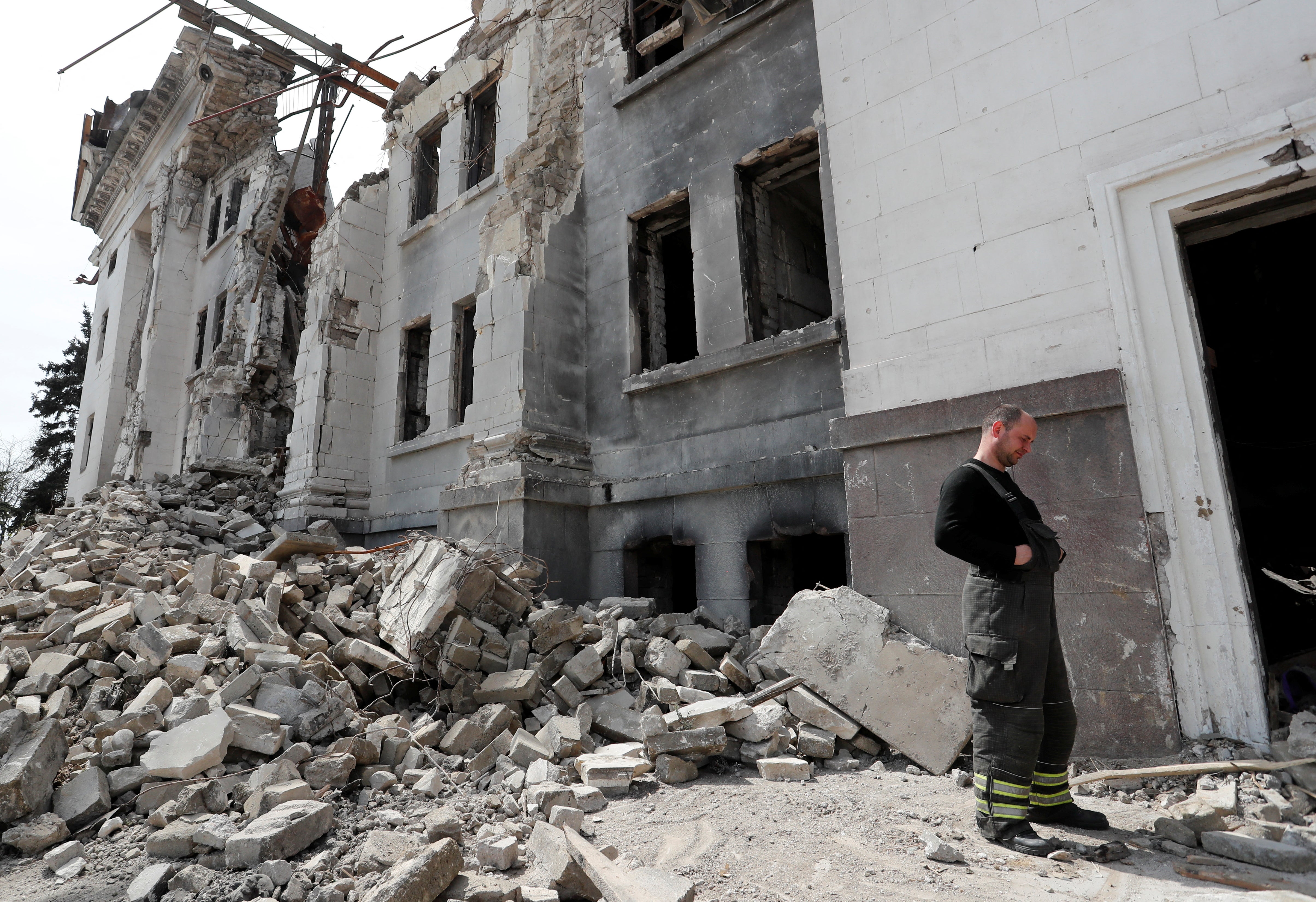 People remove the debris of a theatre building in Mariupol