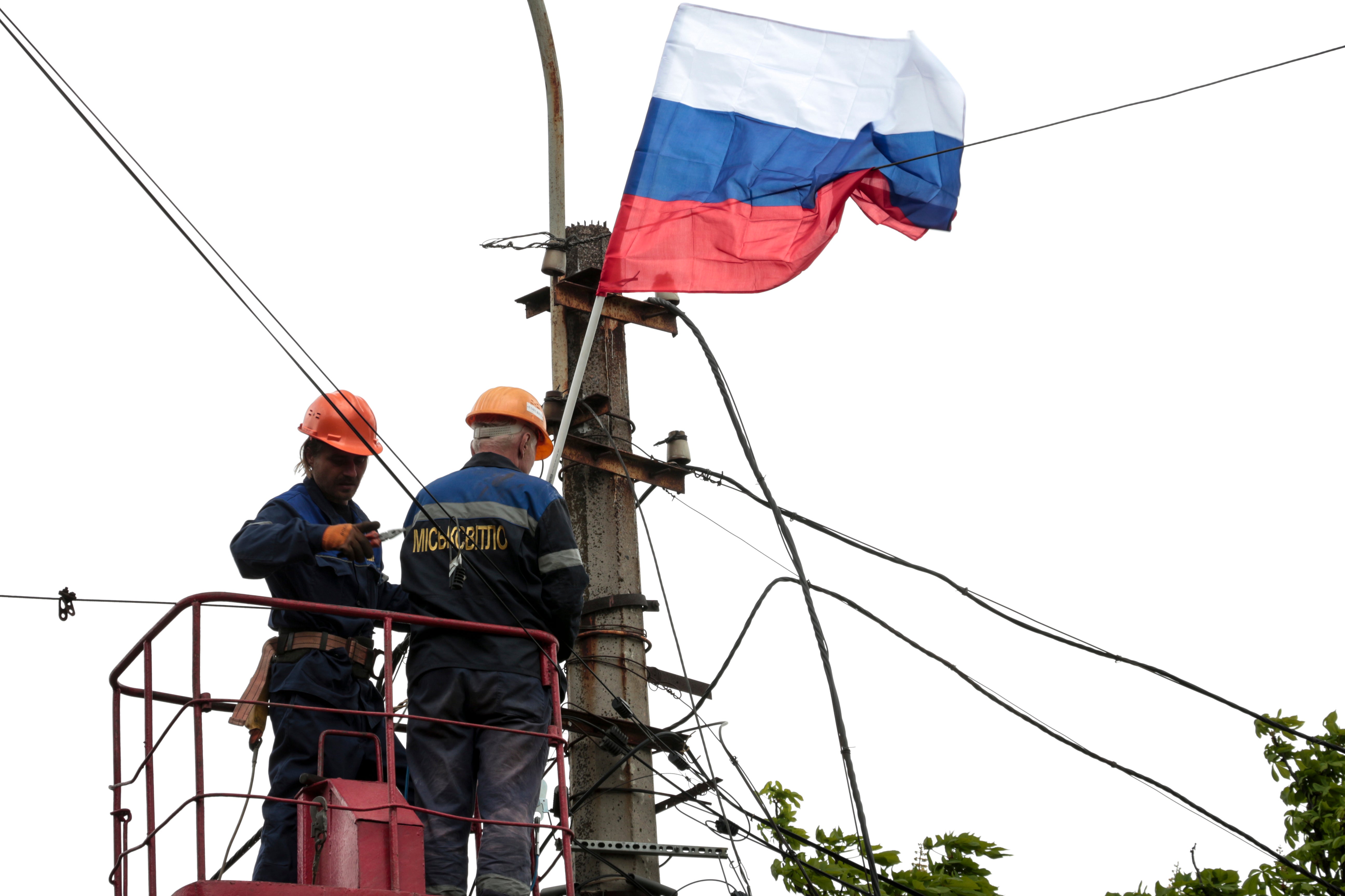 Municipal workers attach a Russian national flag to a pole in Mariupol on Thursday