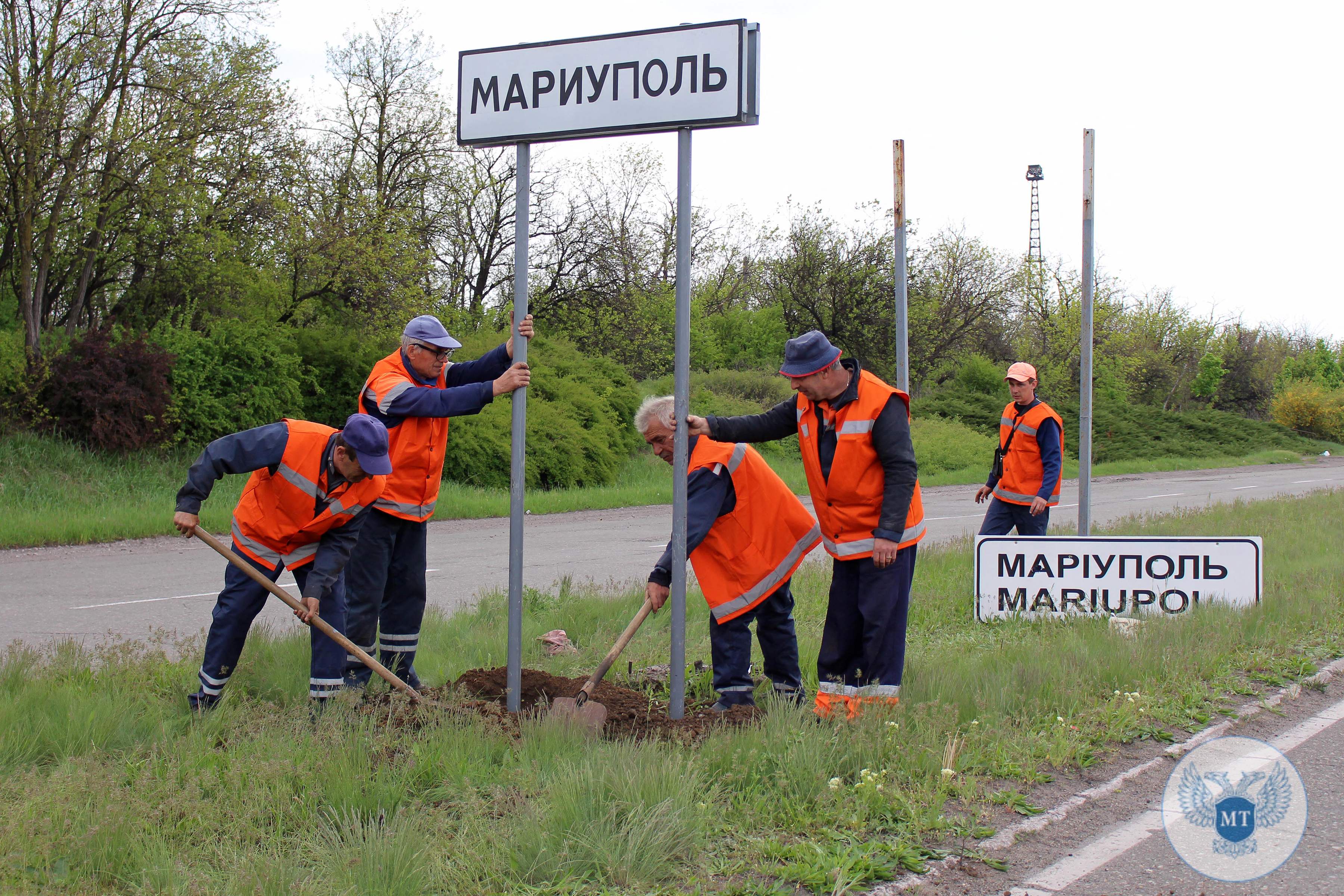 Workers change a road sign outside Mariupol from Ukrainian to Russian language on Thursday