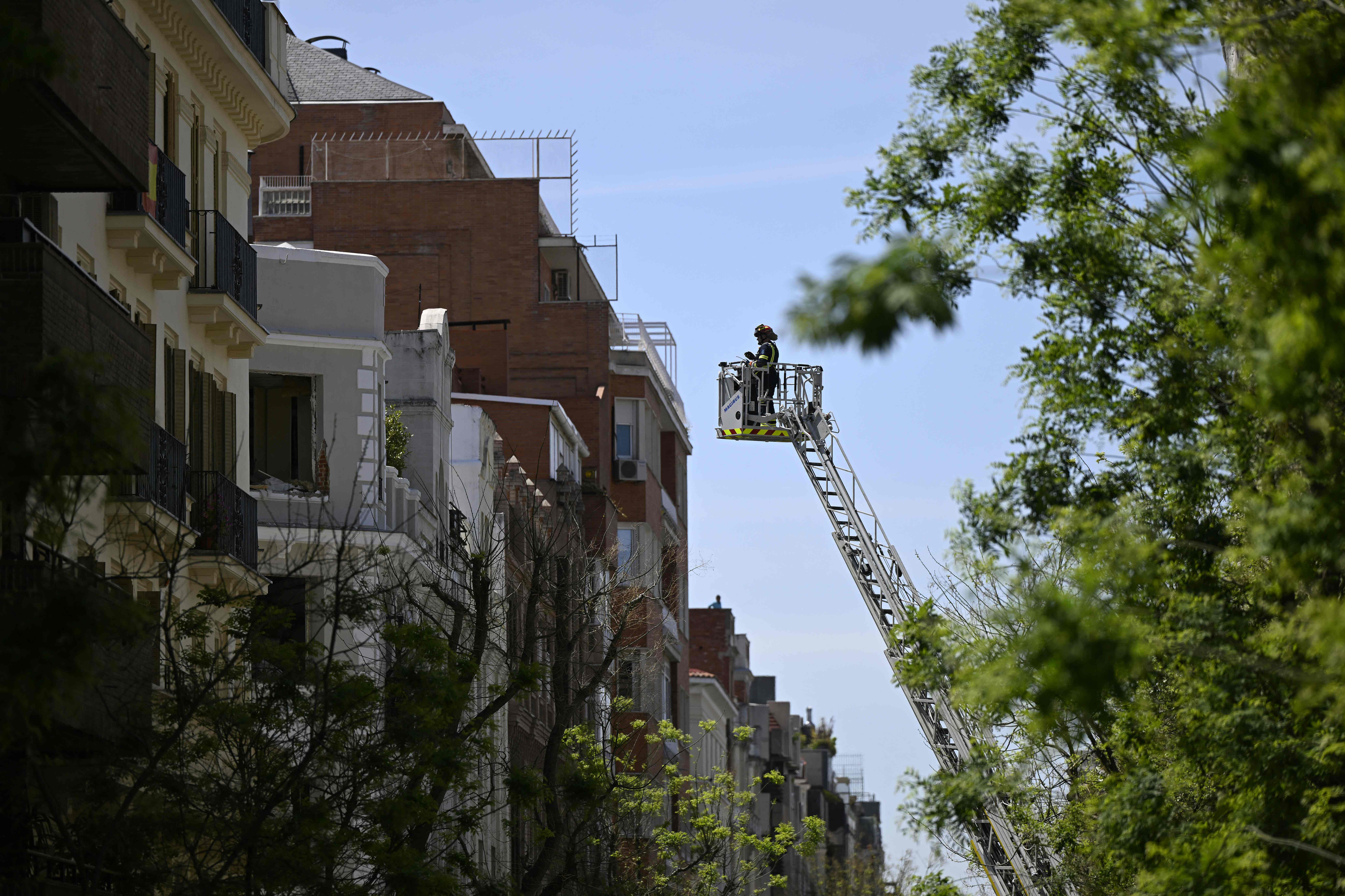 A firefighter inspects a building from a ladder