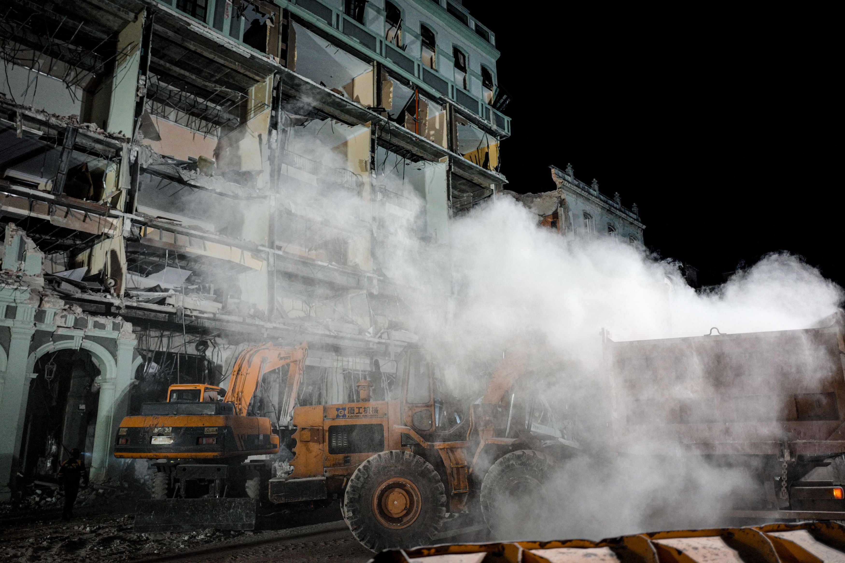 Firefighters and rescue workers remove debris from the ruins of the Saratoga Hotel