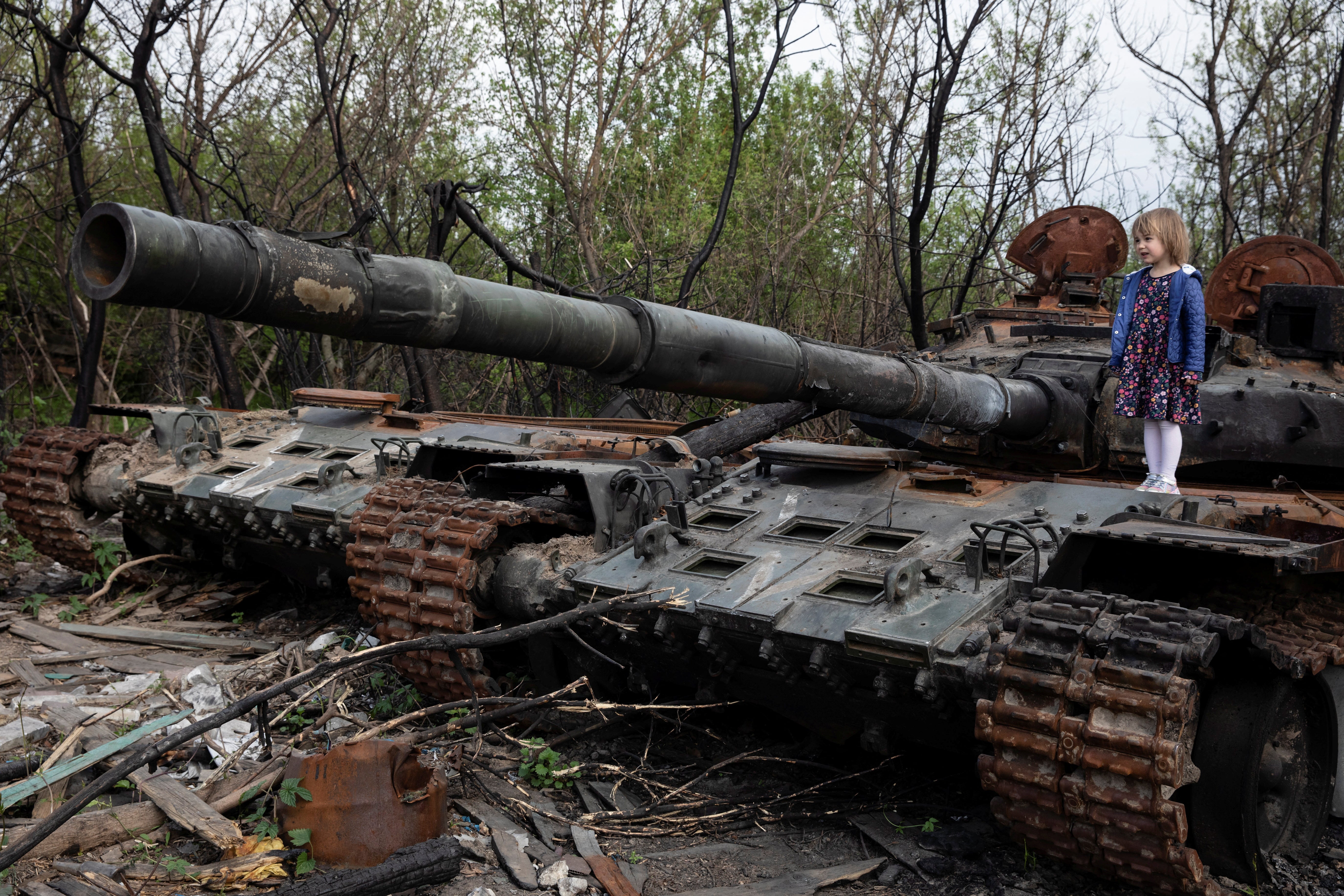 A child stands on a destroyed Russian tank near Makariv, Kyiv