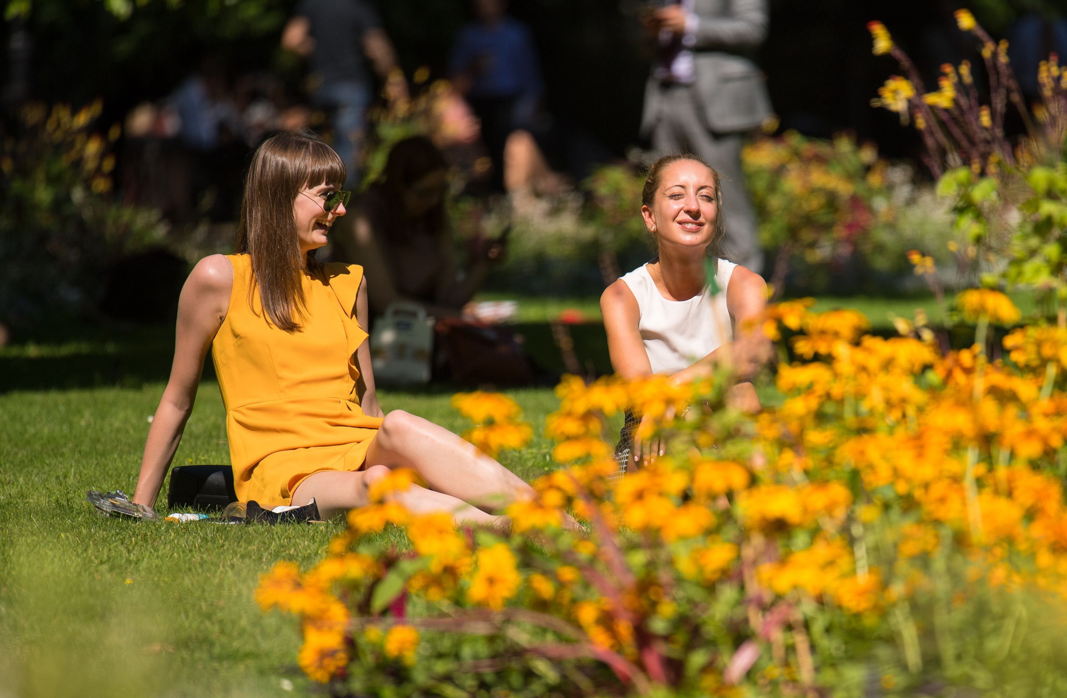 Two women sit in the sun in Whitehall Gardens, Westminster (Dominic Lipinski/PA)