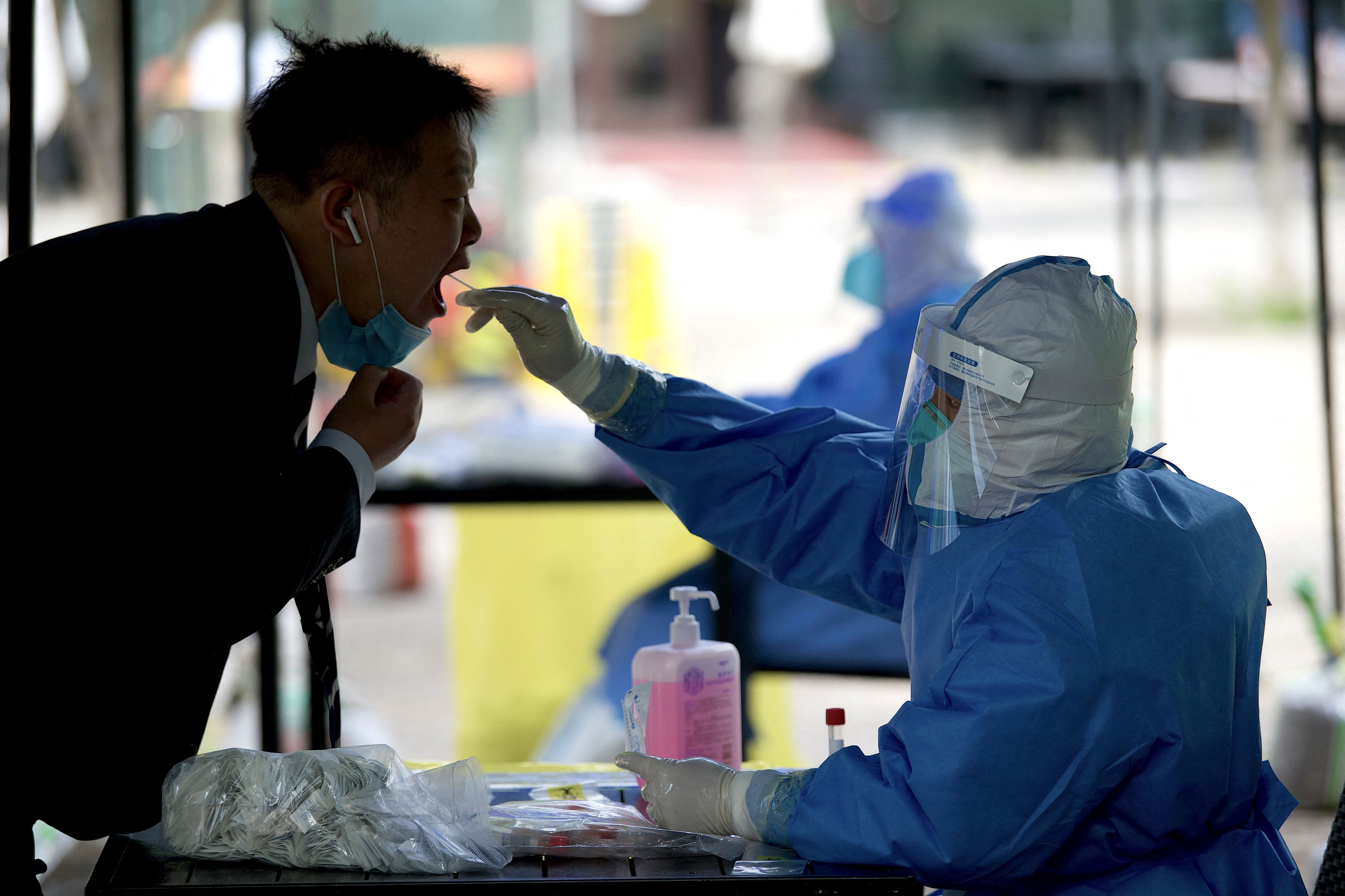 A health worker takes a sample from a man to test for the Covid-19 infection in Beijing