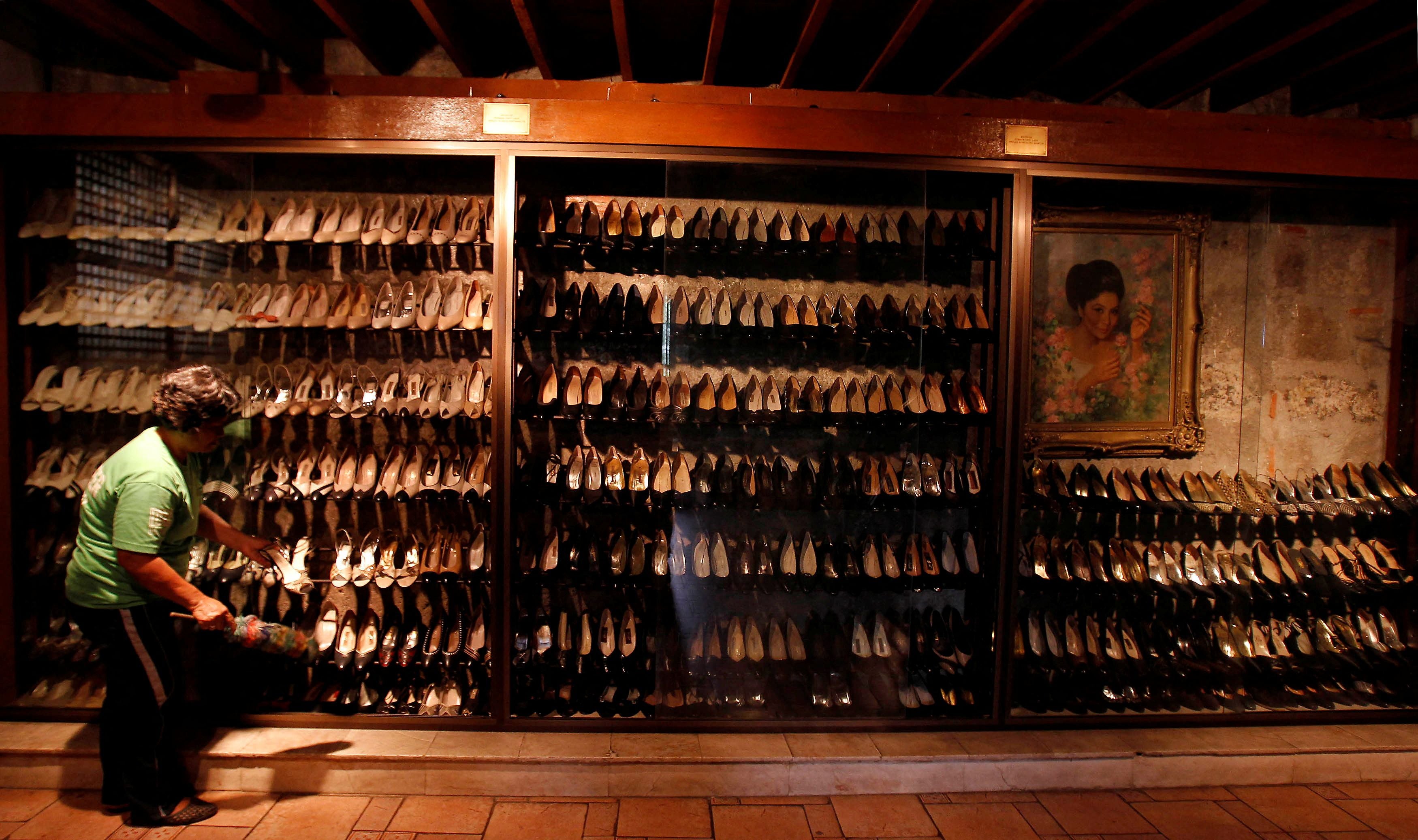 A volunteer cleans shoes of Marcos on display at Marikina Shoe Museum