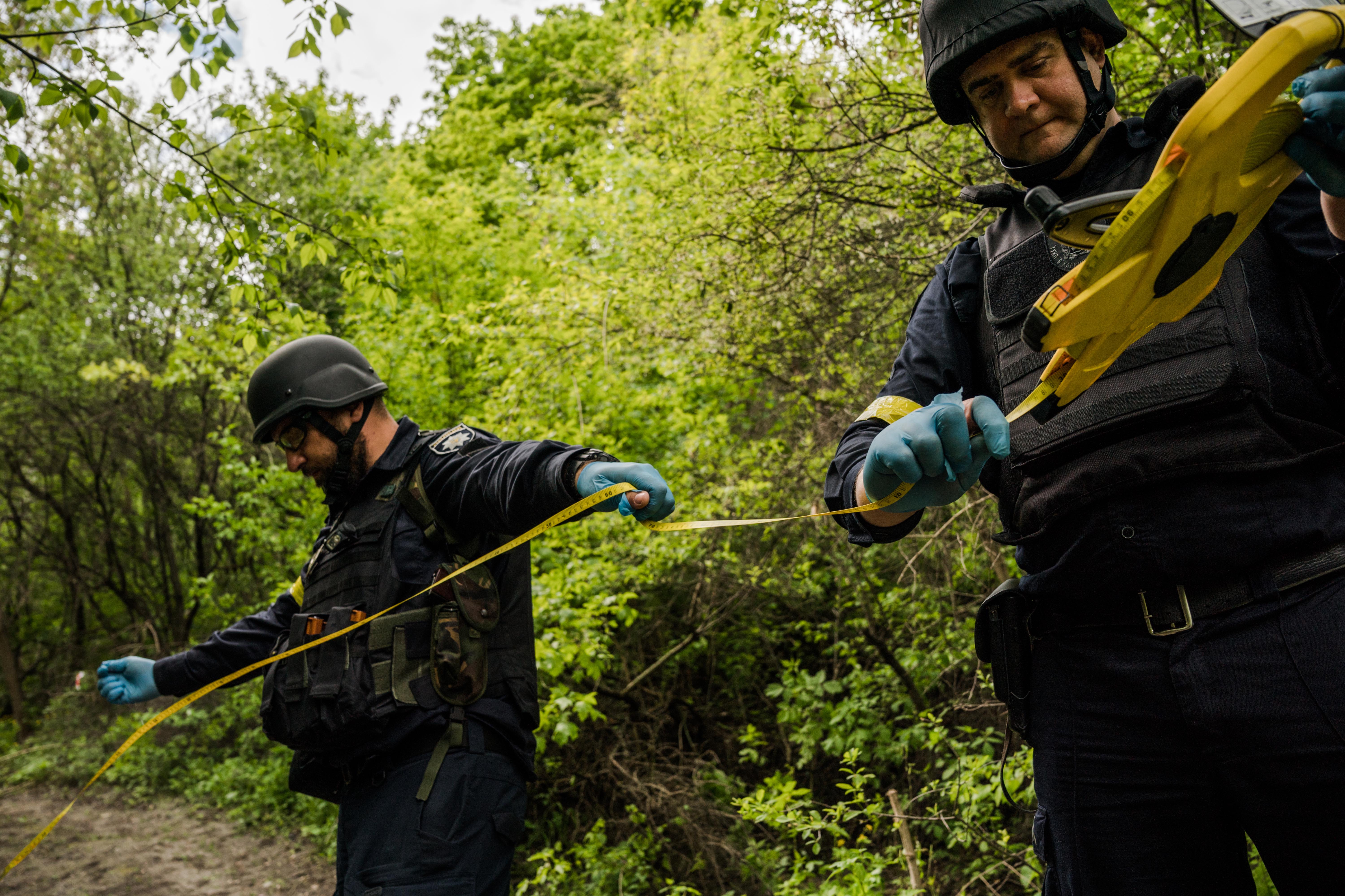 Criminologist Oleksandr Bogdanov, left, and Bogdan Burgelo, head of the forensic support department, prepare the scene where the women were found