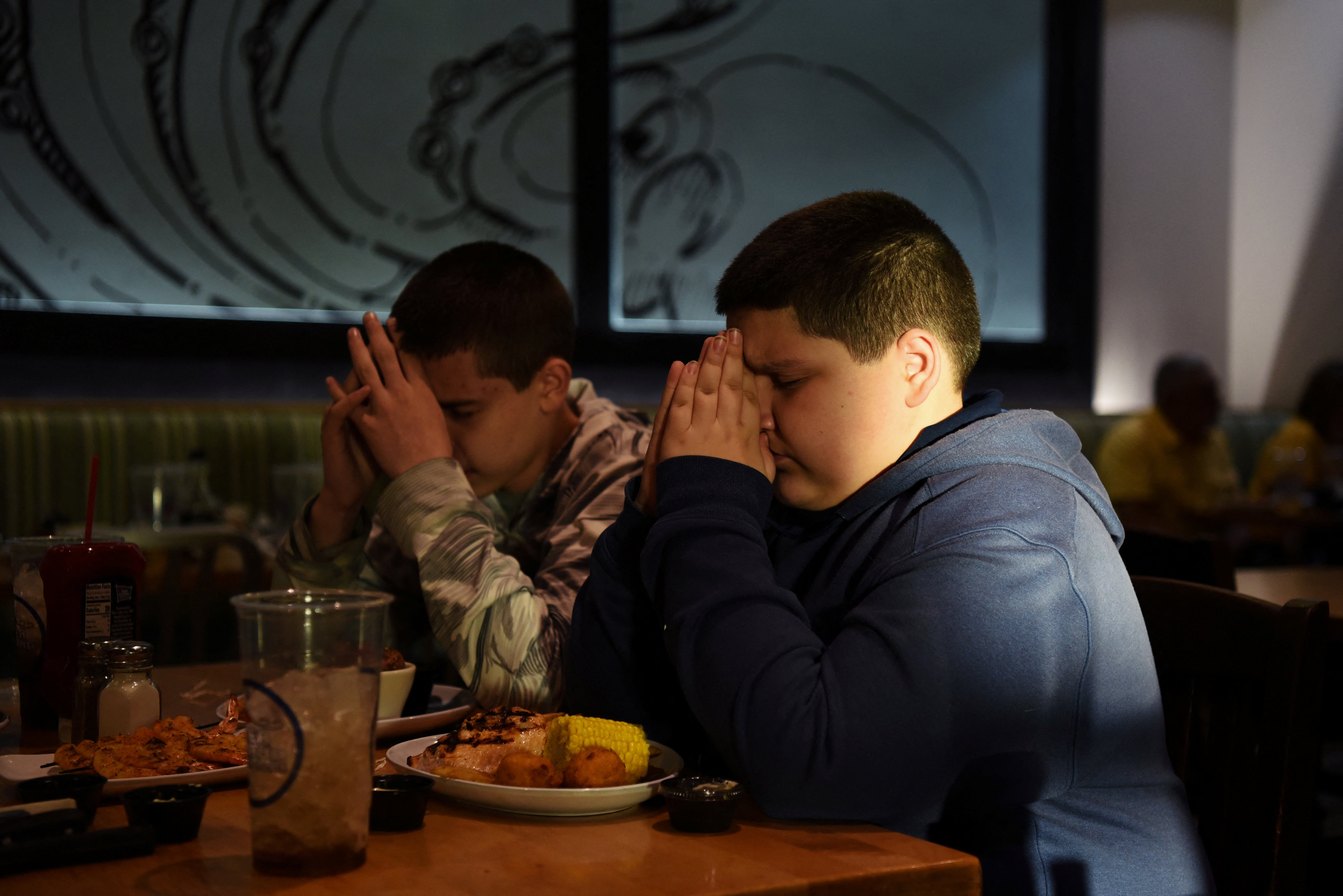 Brothers Julius Garza and Aidan Garza say a prayer in honour of their father, David Garza