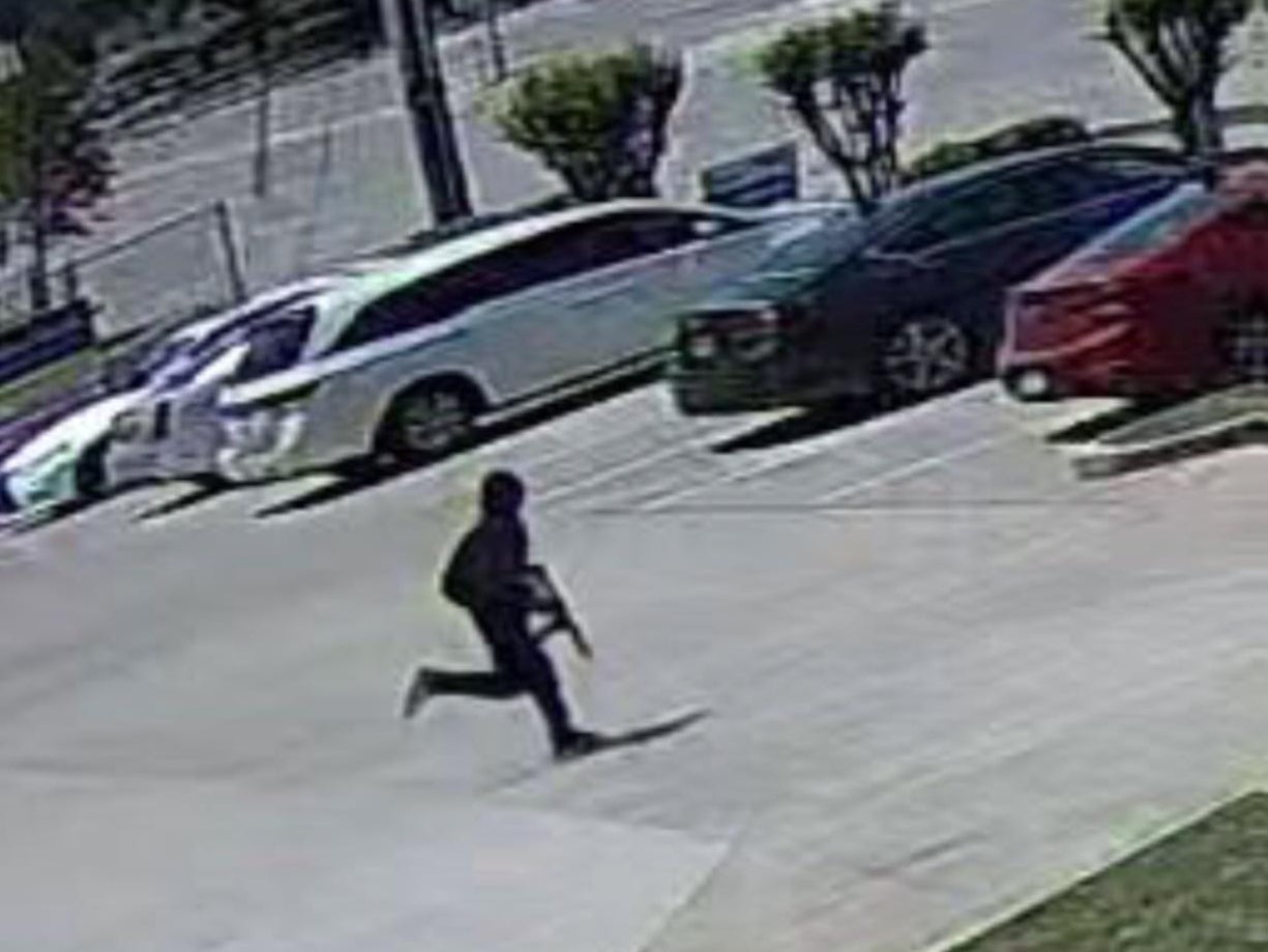 A still image released by Dallas Police shows a shooting suspect running in a parking lot after allegedly opening fire in a hair salon