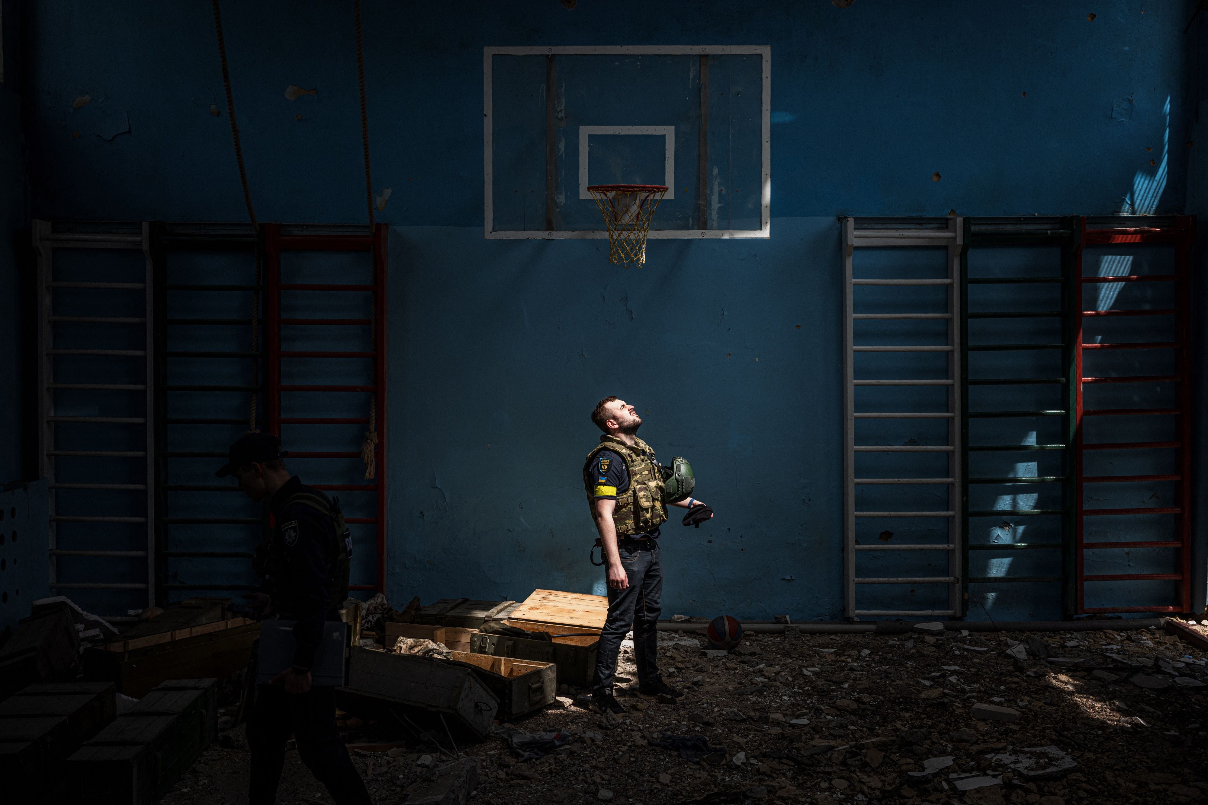 A Ukrainian policeman stands inside the sports hall of a battered school in Vilkhivka