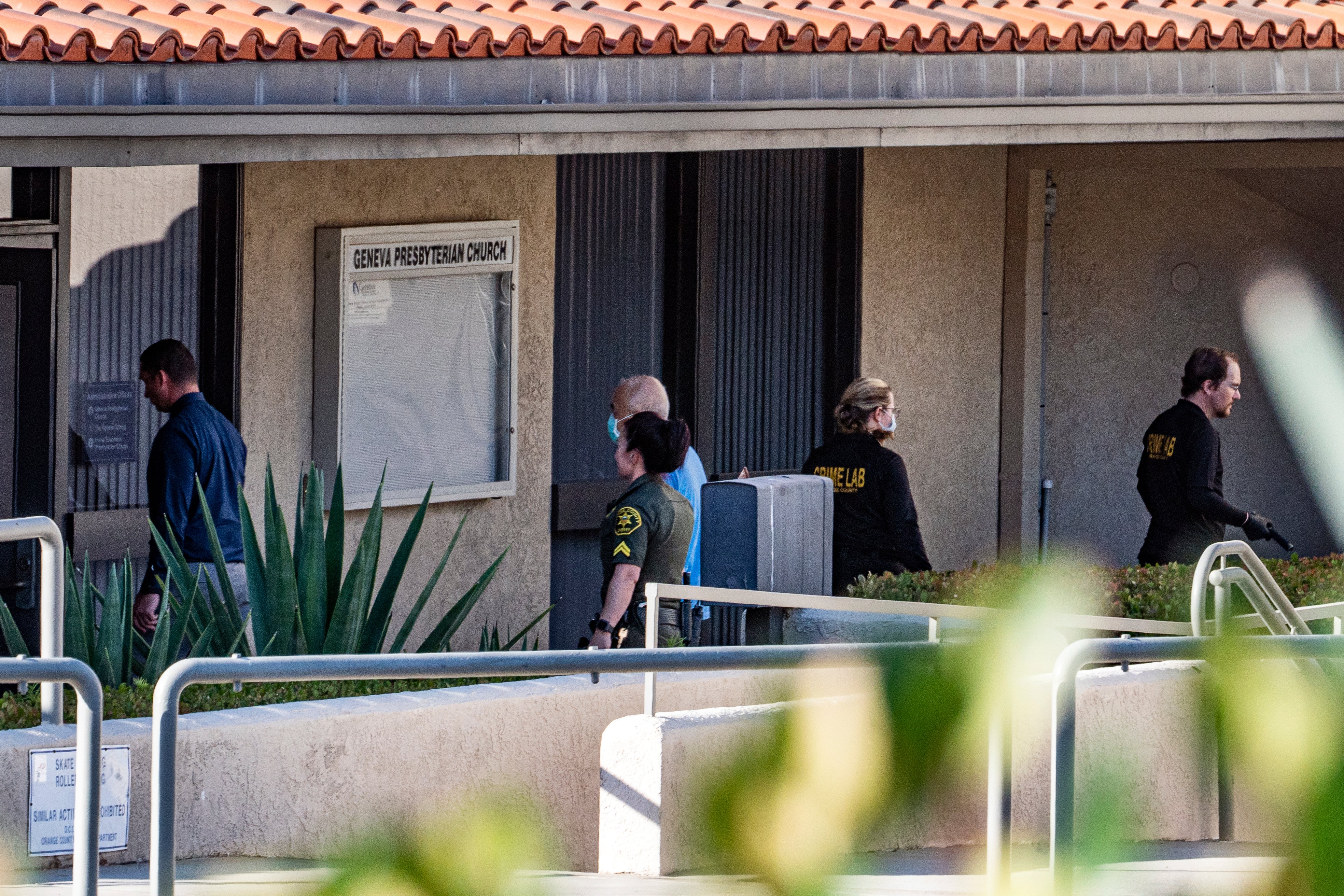 Orange County sheriff’s department crime lab investigators walk outside the Geneva Presbyterian Church in Laguna Woods