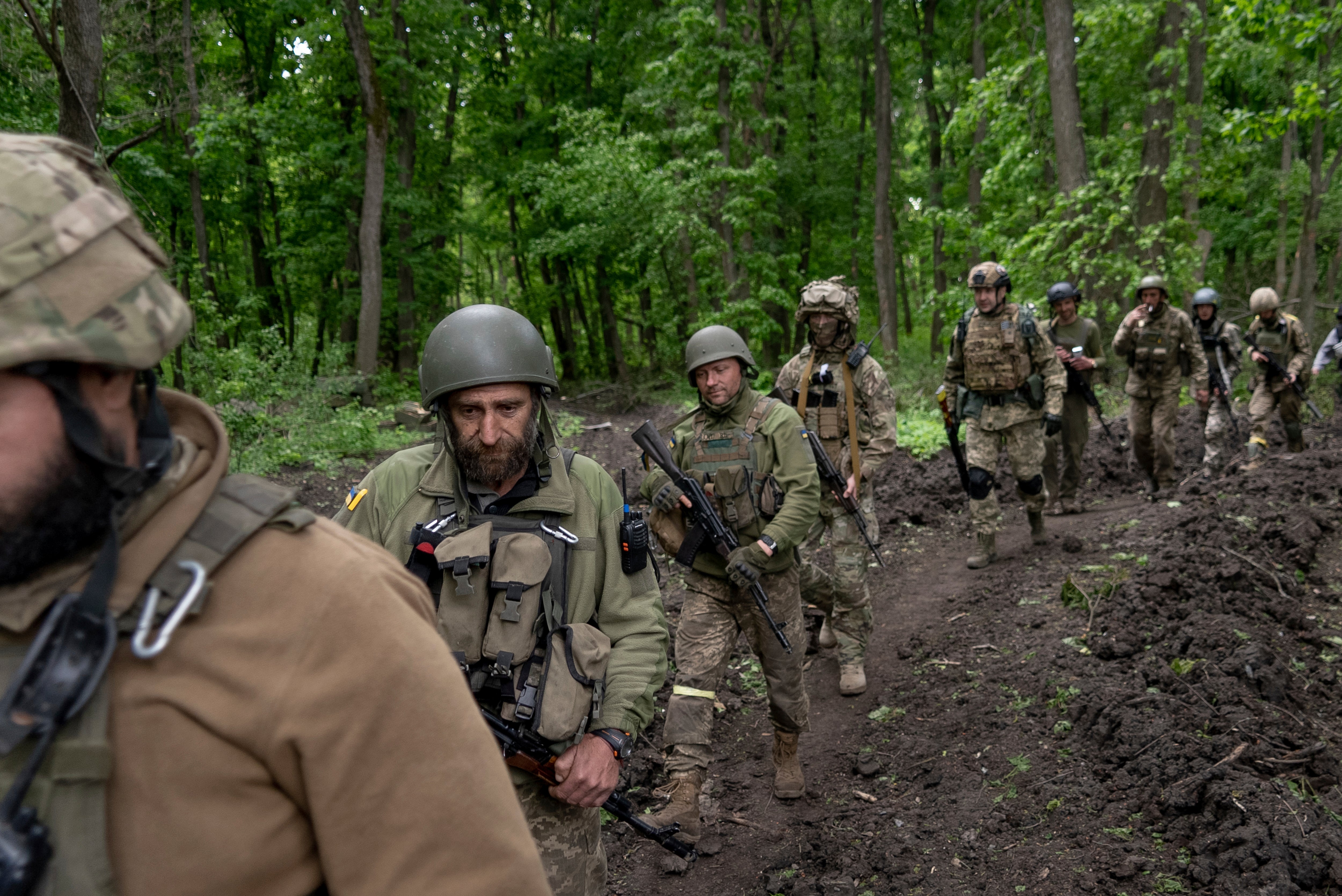 Ukrainian soldiers walk in a forest near a recently recaptured village to the north of Kharkiv on 15 May, 2022