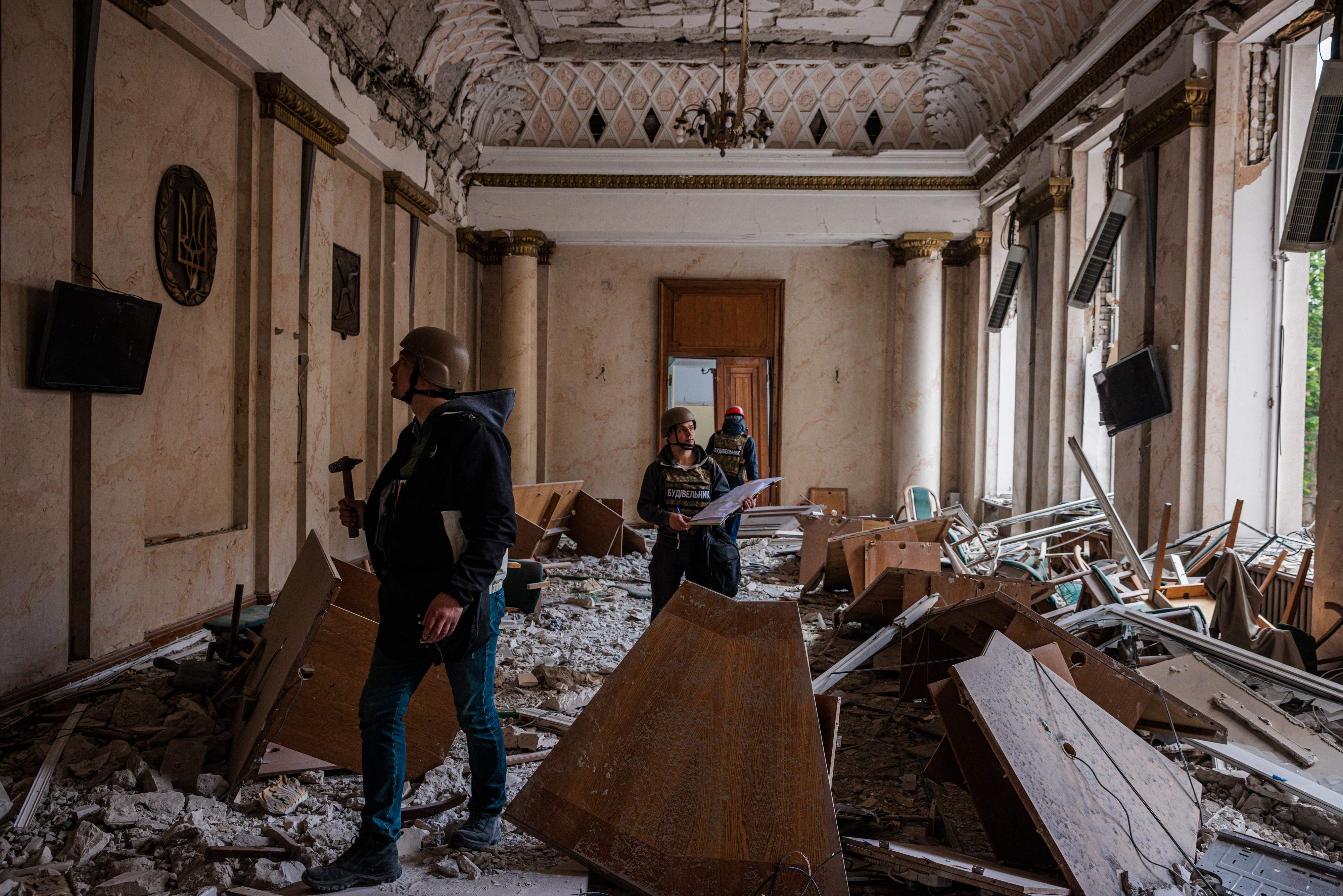 Engineers examine a damaged official building in Kharkiv on Monday after it was bombed by Russian forces