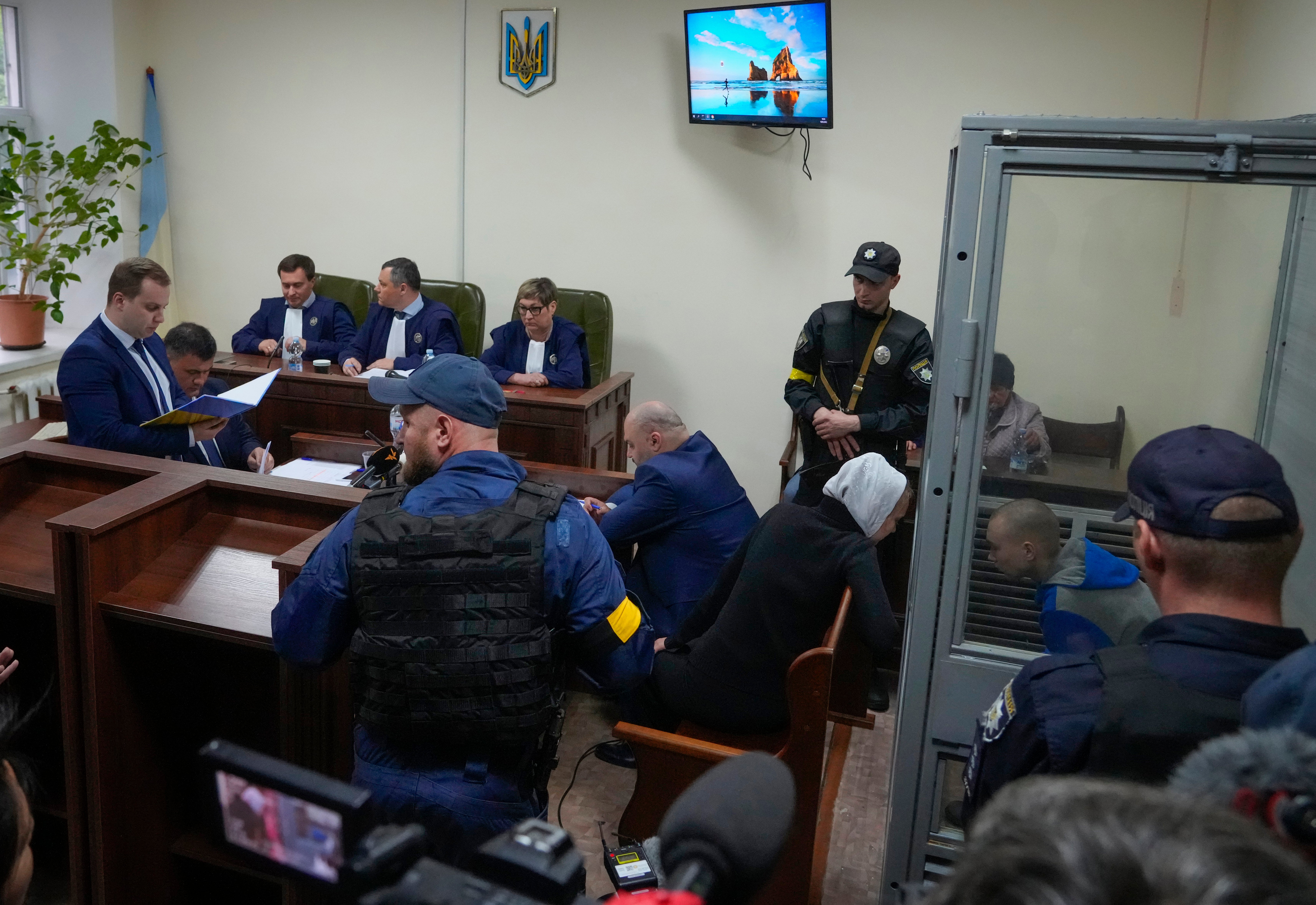 Shishimarin behind glass speaking to his translator at the court in Kyiv