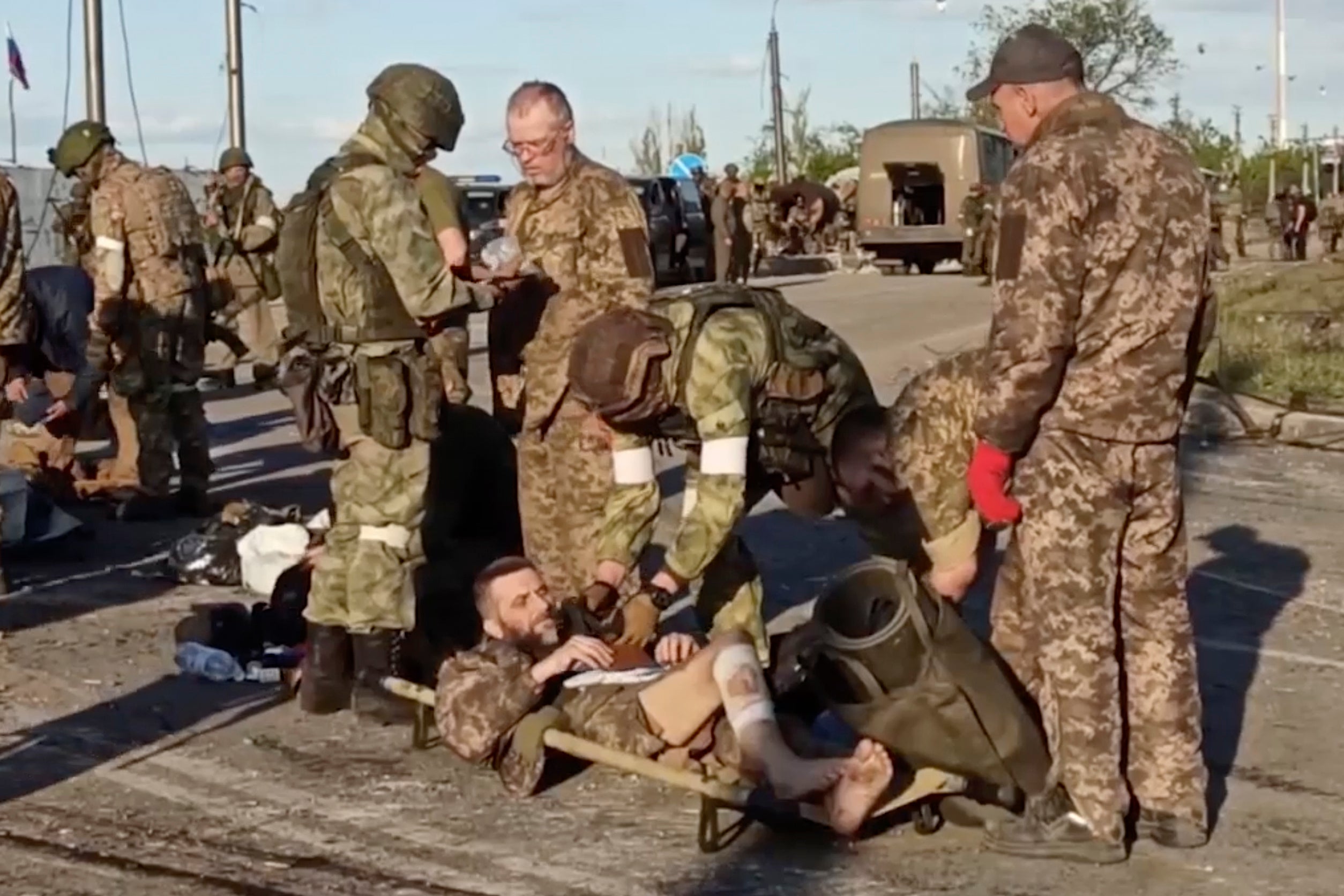 Russian servicemen frisk Ukrainian servicemen as they are being evacuated from the besieged Azovstal steel plant