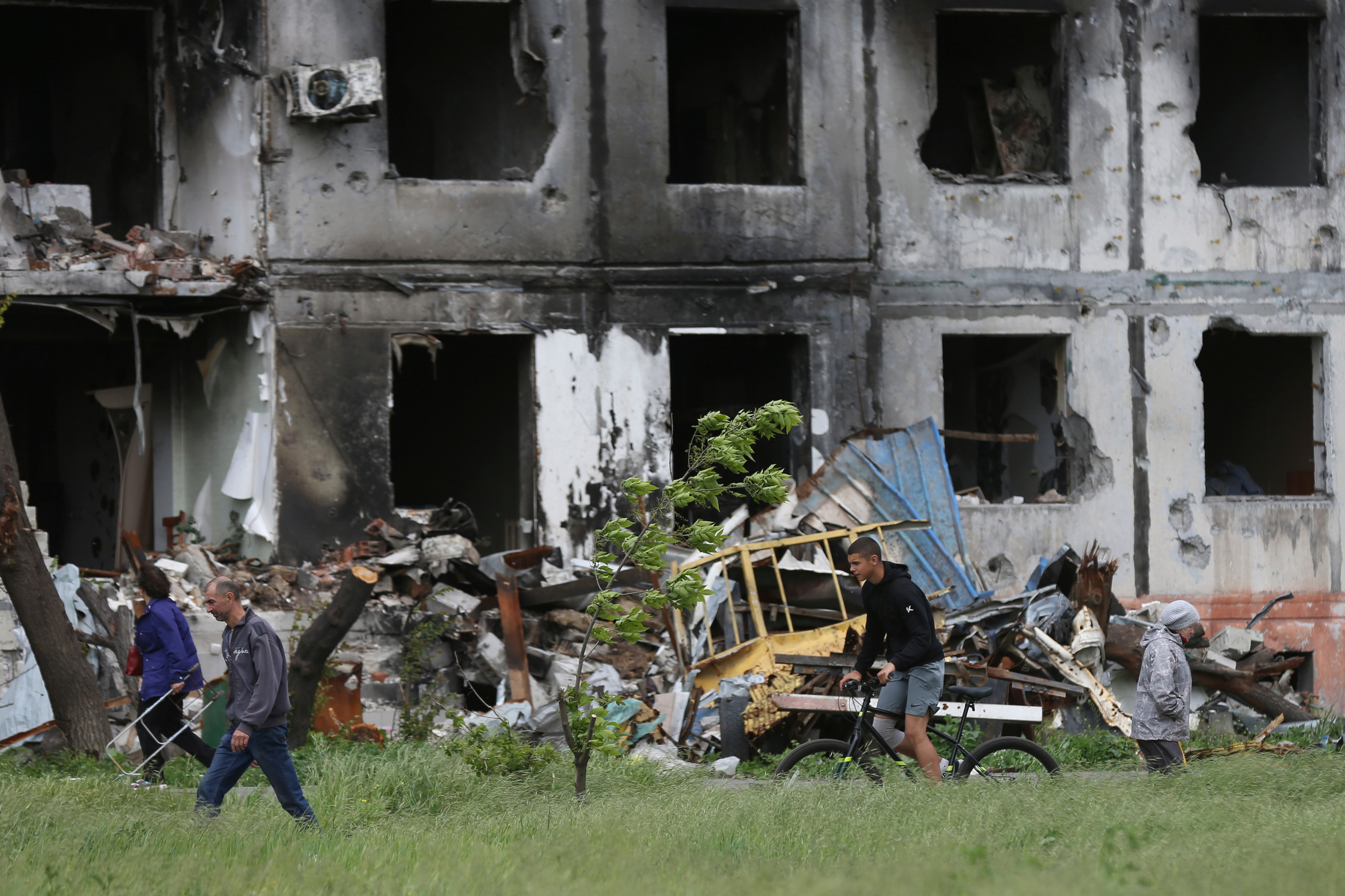 People walk past a destroyed building in Mariupol, in territory under the government of the Donetsk People's Republic