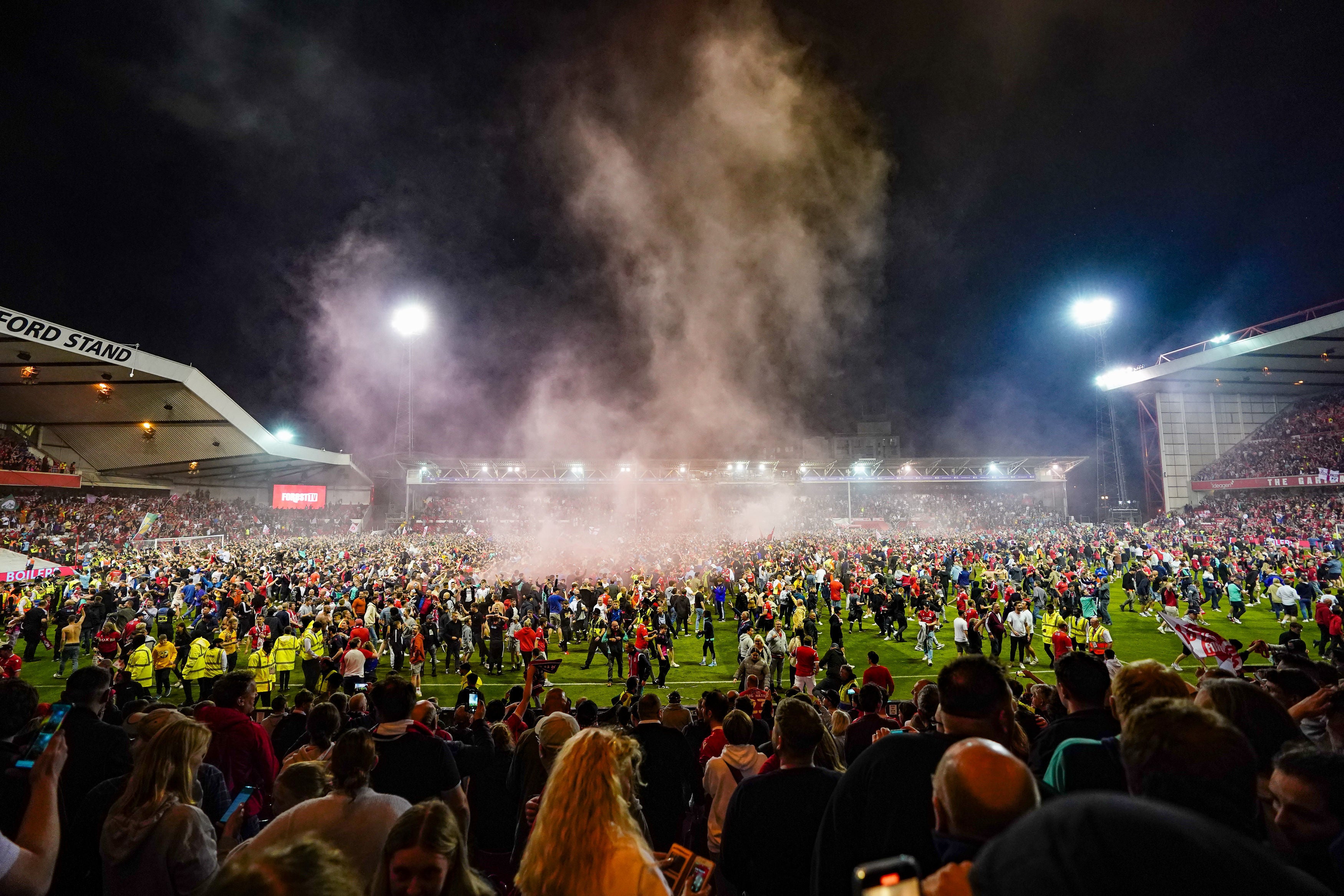 Nottingham Forest fans celebrate on the pitch after they reach the play-off final at City Ground on Tuesday