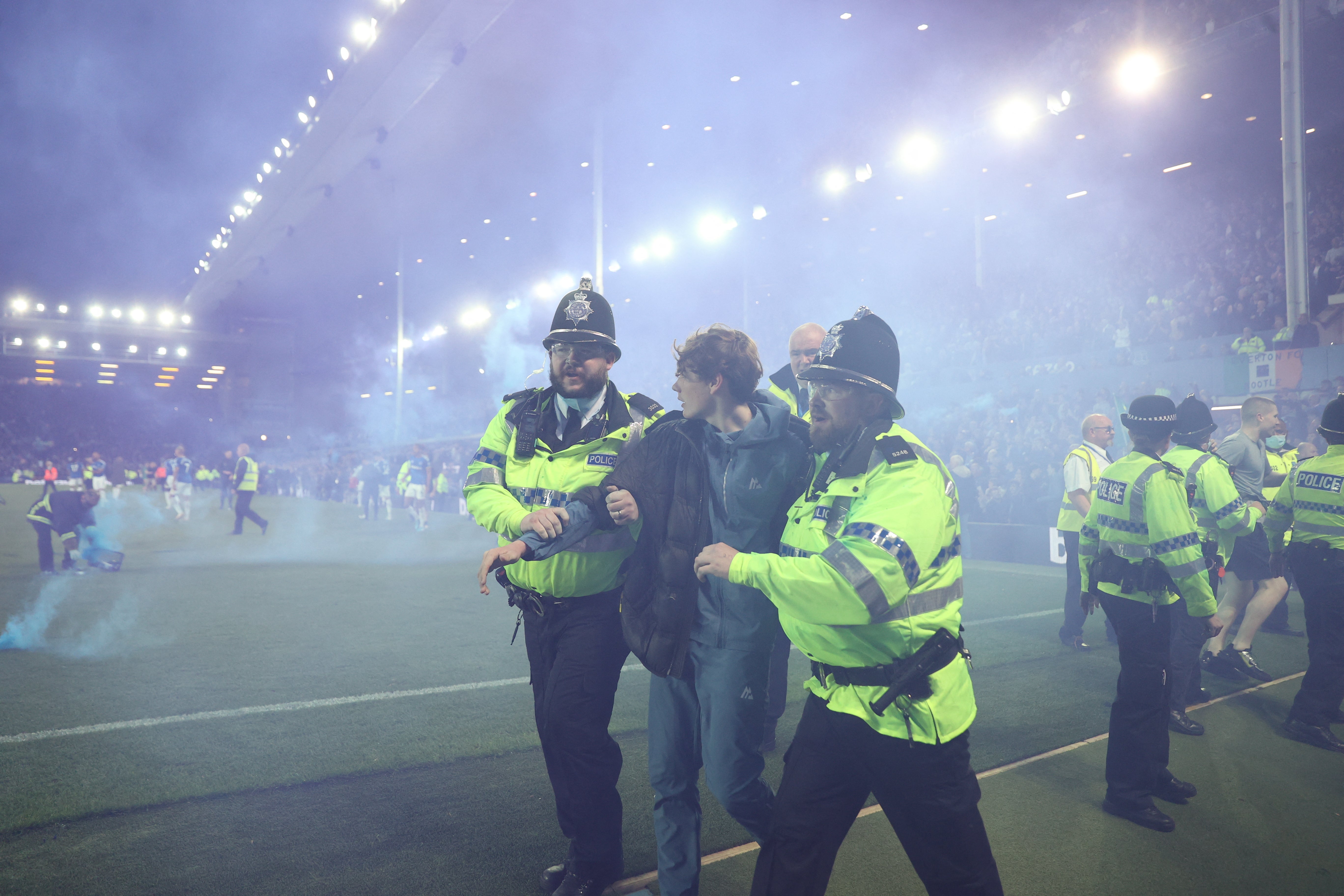 Police officers detain Everton fans during a pitch invasion on Thursday