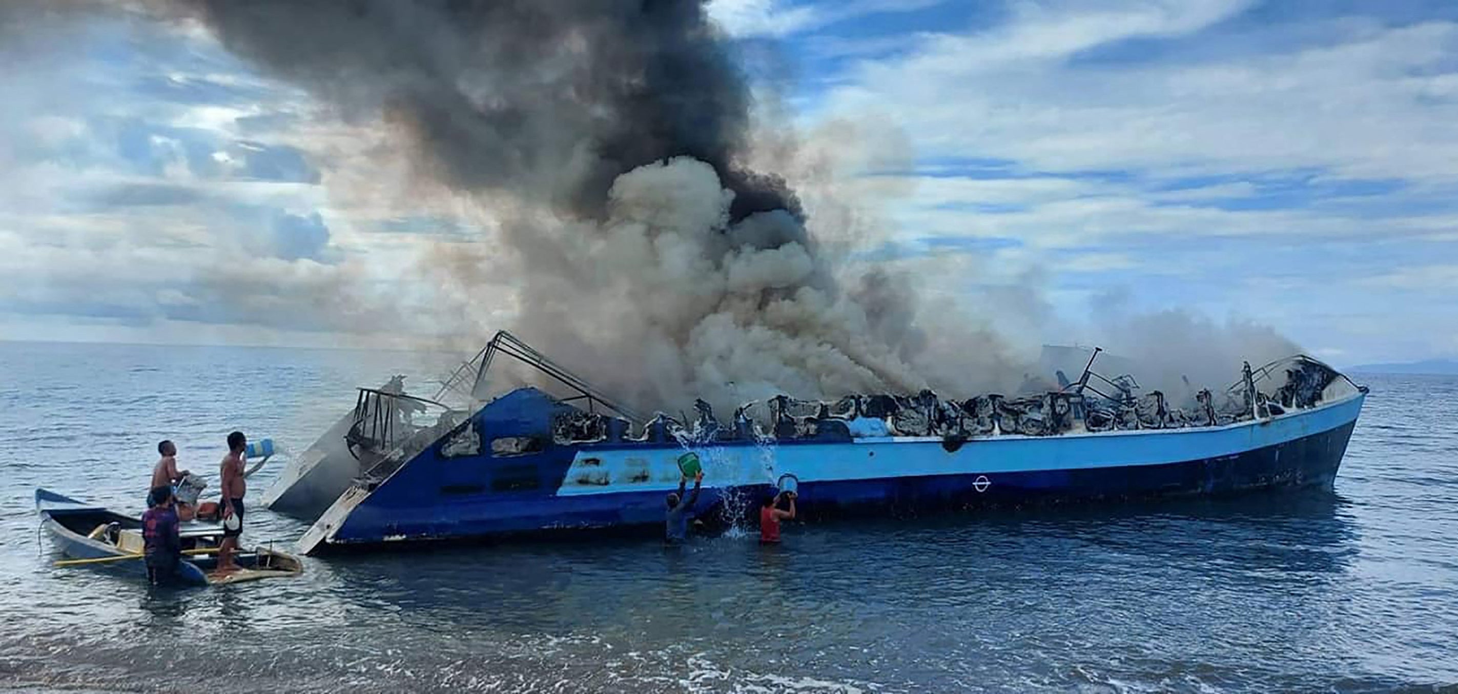 People throwing buckets of water onto a smouldering ferry