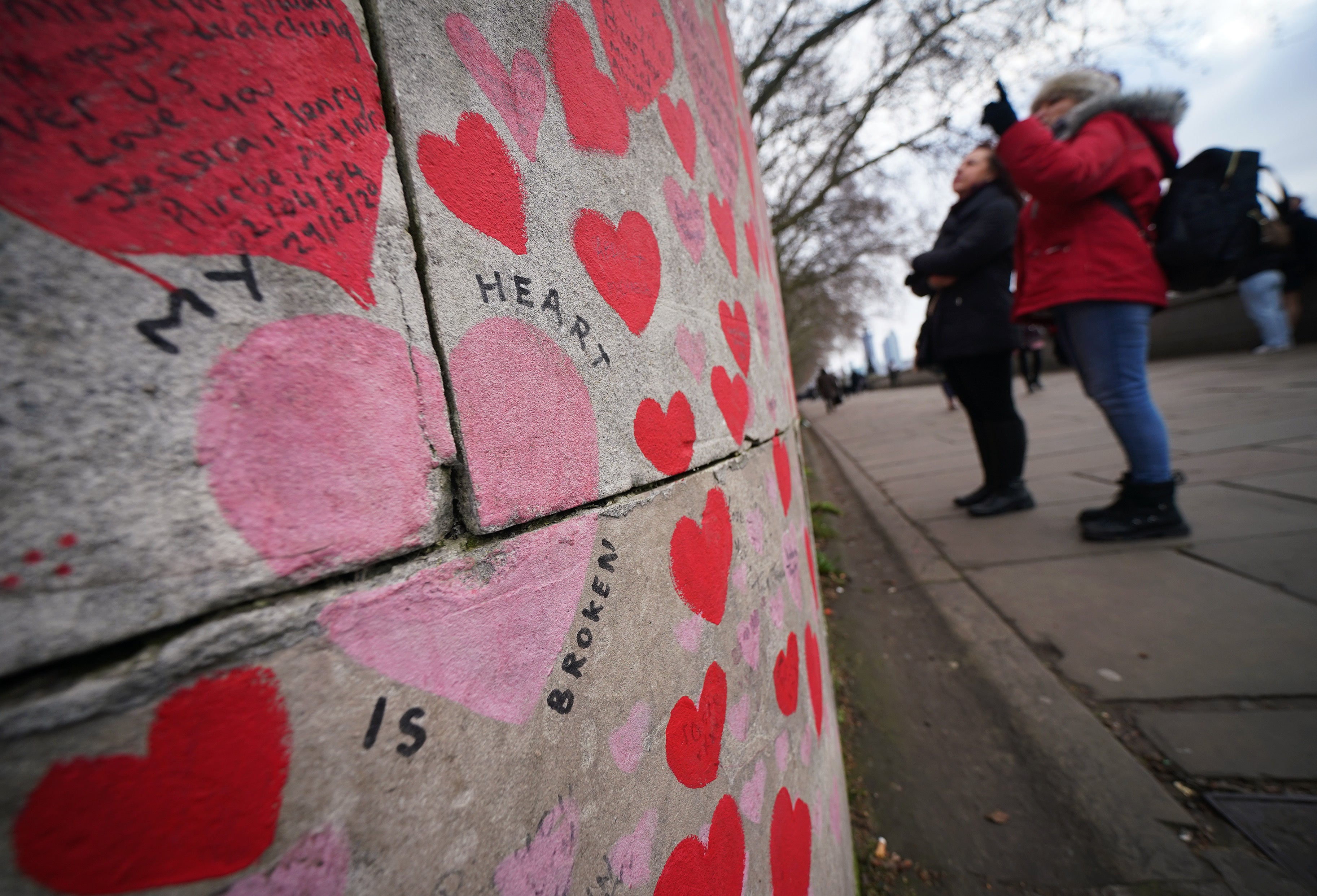 People stop to look at tributes on the Covid memorial wall in central London (Yui Mok/PA)