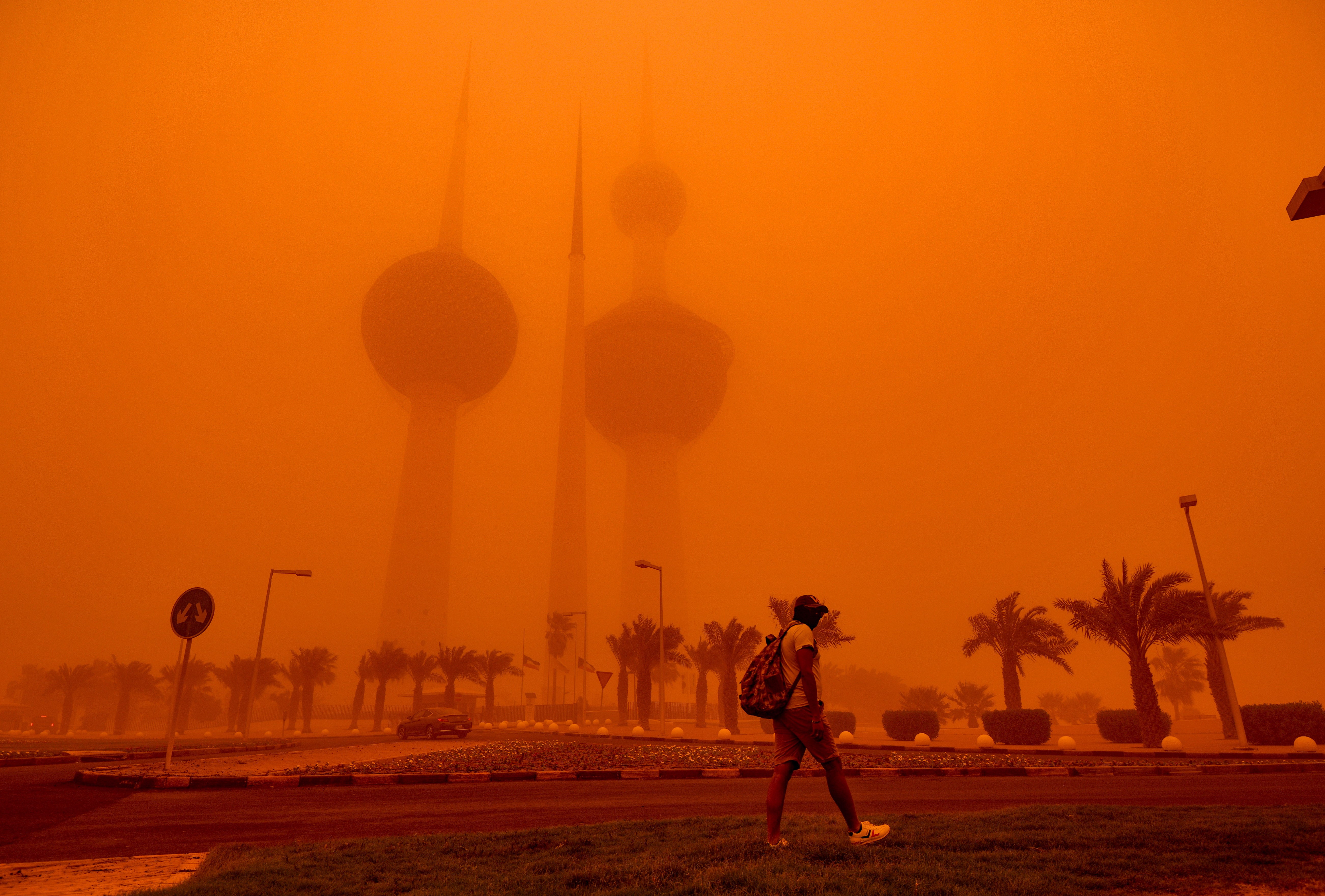A man walks past the Kuwait Towers shrouded in heavy dust in Kuwait City