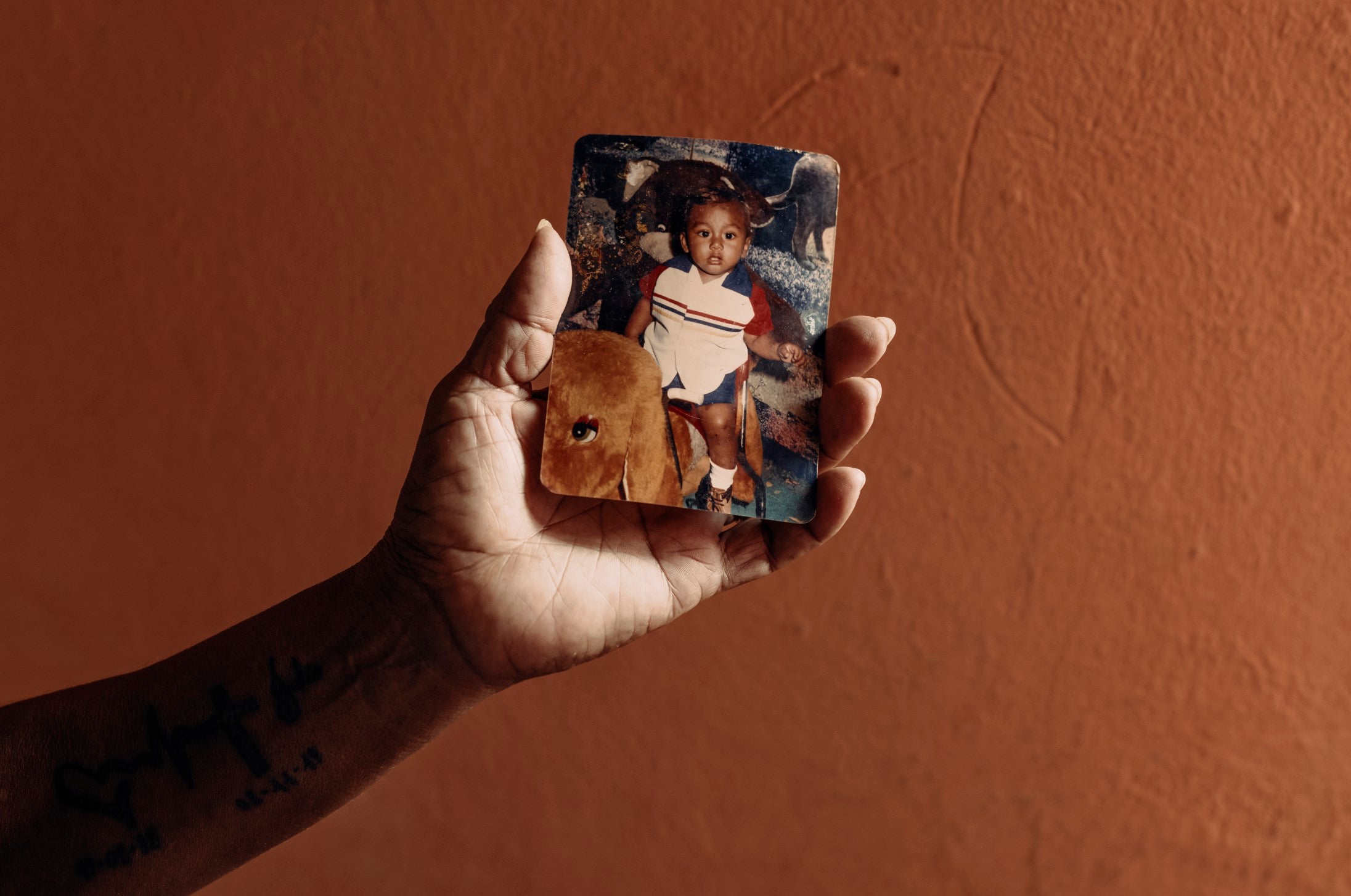 Delphine holds a photograph of her murdered son, Julio, who was recruited by a gang while serving a prison sentence for possession of marijuana and killed just metres from their home