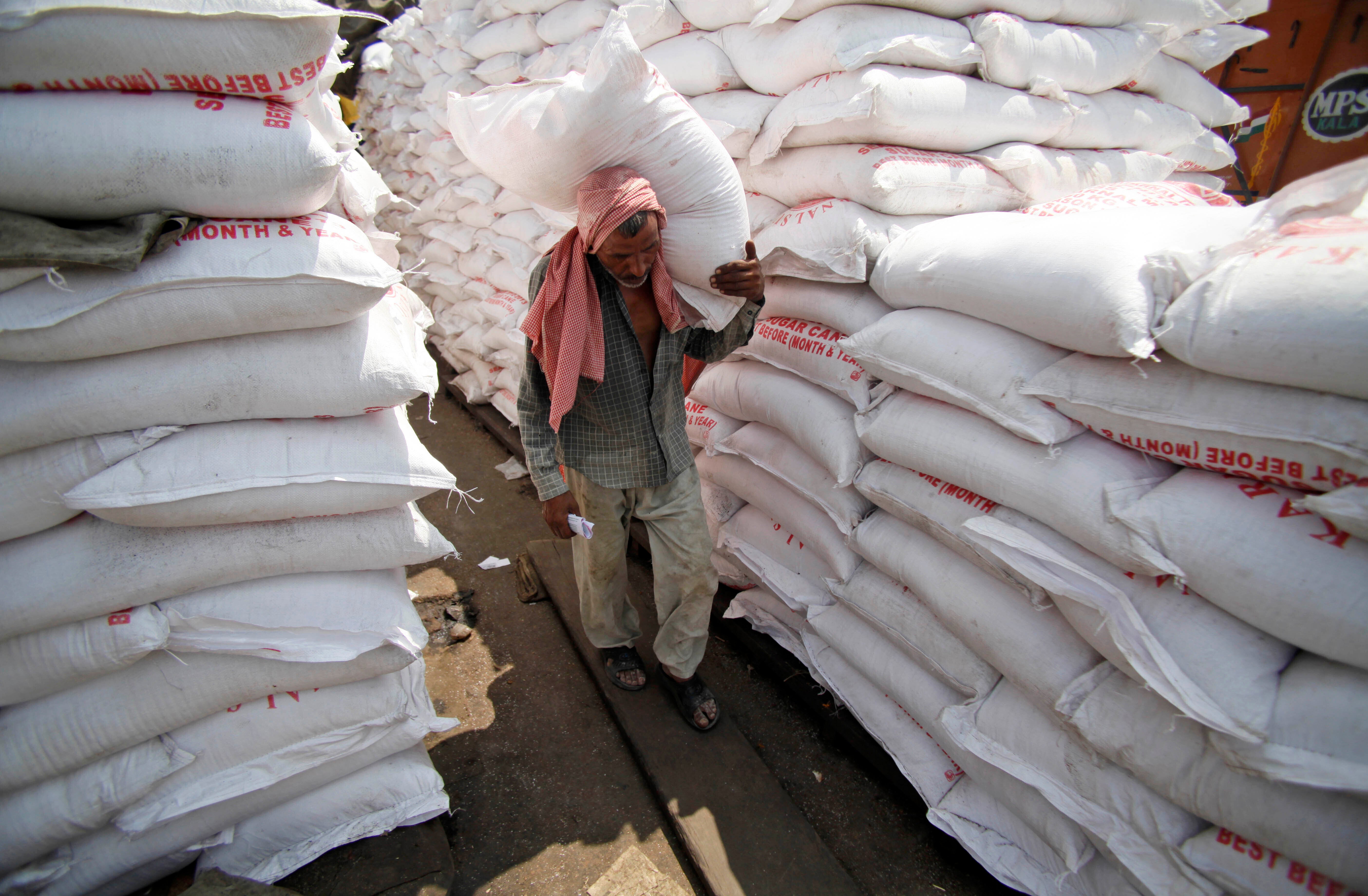 A labourer carries a sack of sugar at a warehouse in Jammu, India