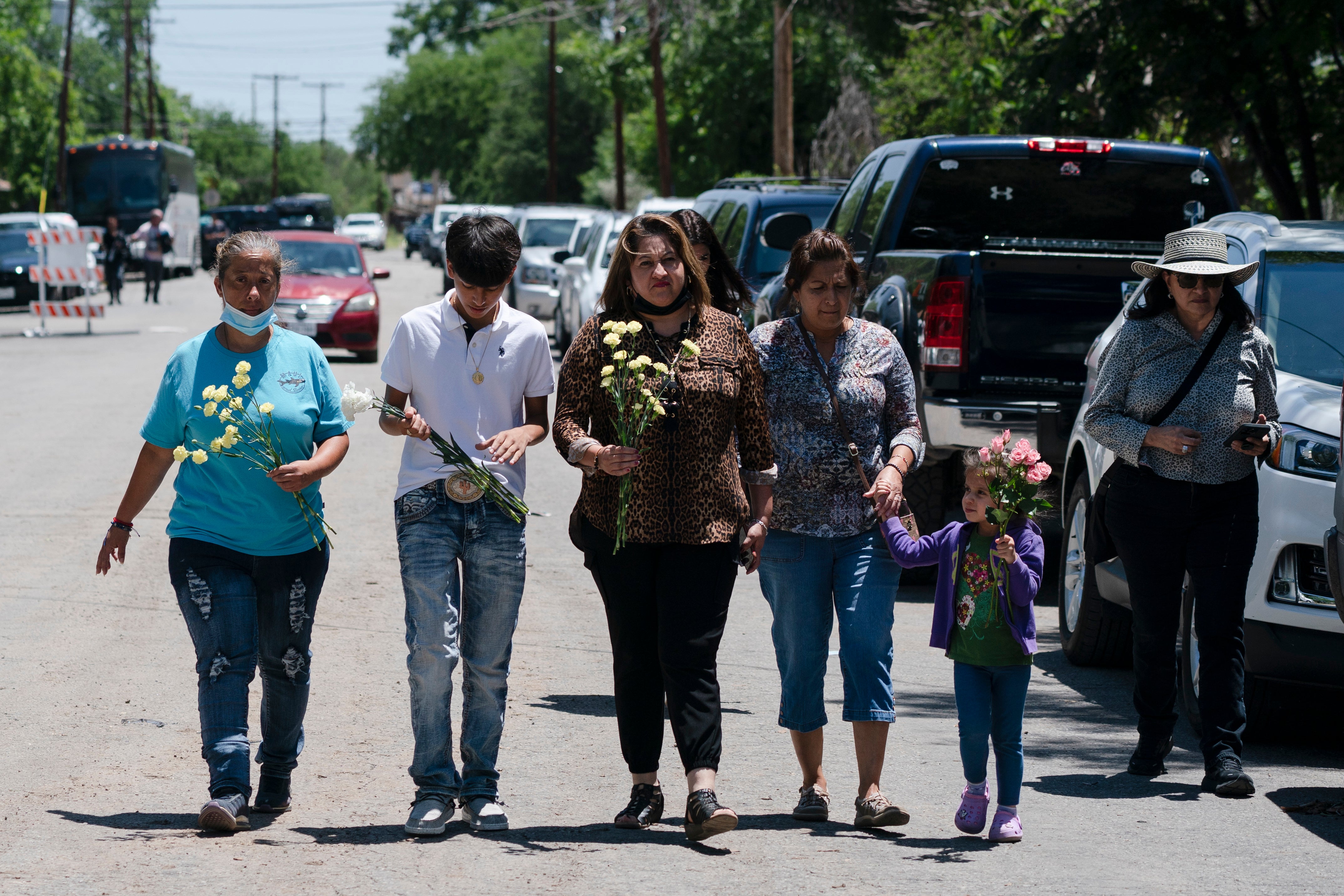 People walk with flowers to honor the victims in Tuesday’s shooting at Robb Elementary School