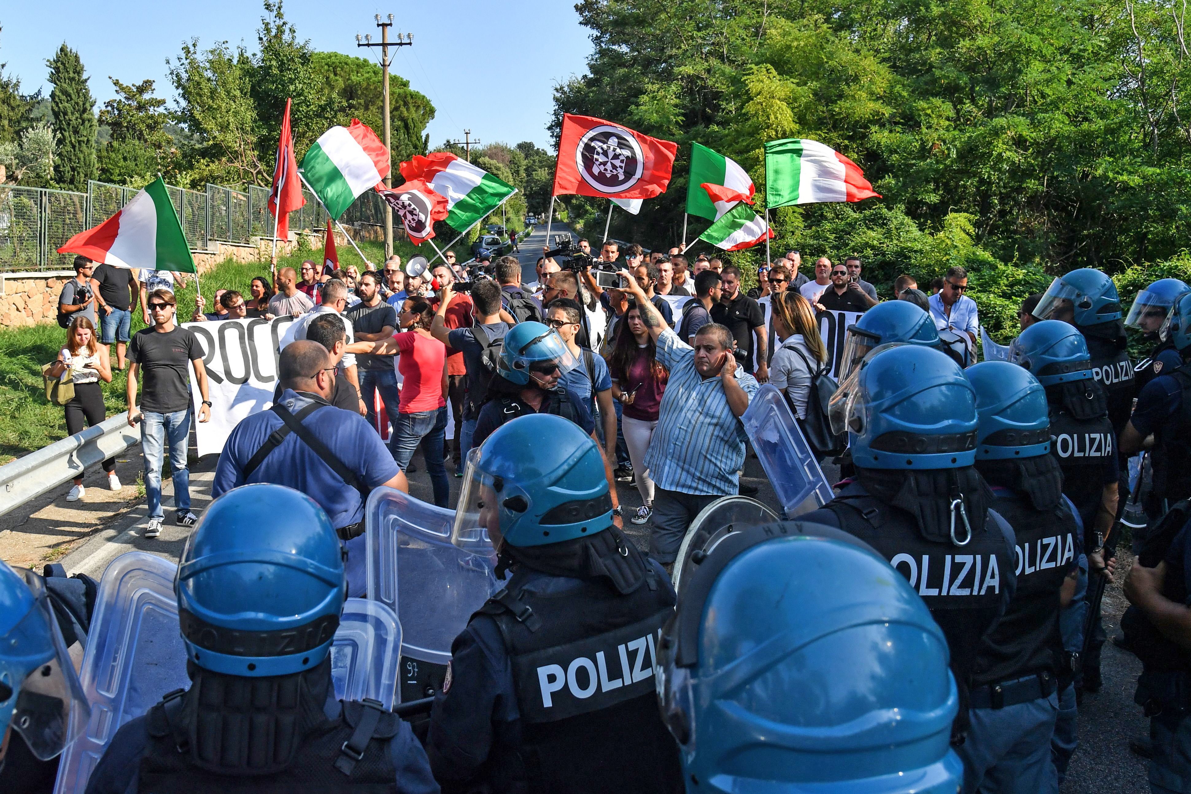 CasaPound activists are watched by police officials as they protest against the arrival of migrants in Rocca di Papa, near Rome, 2018