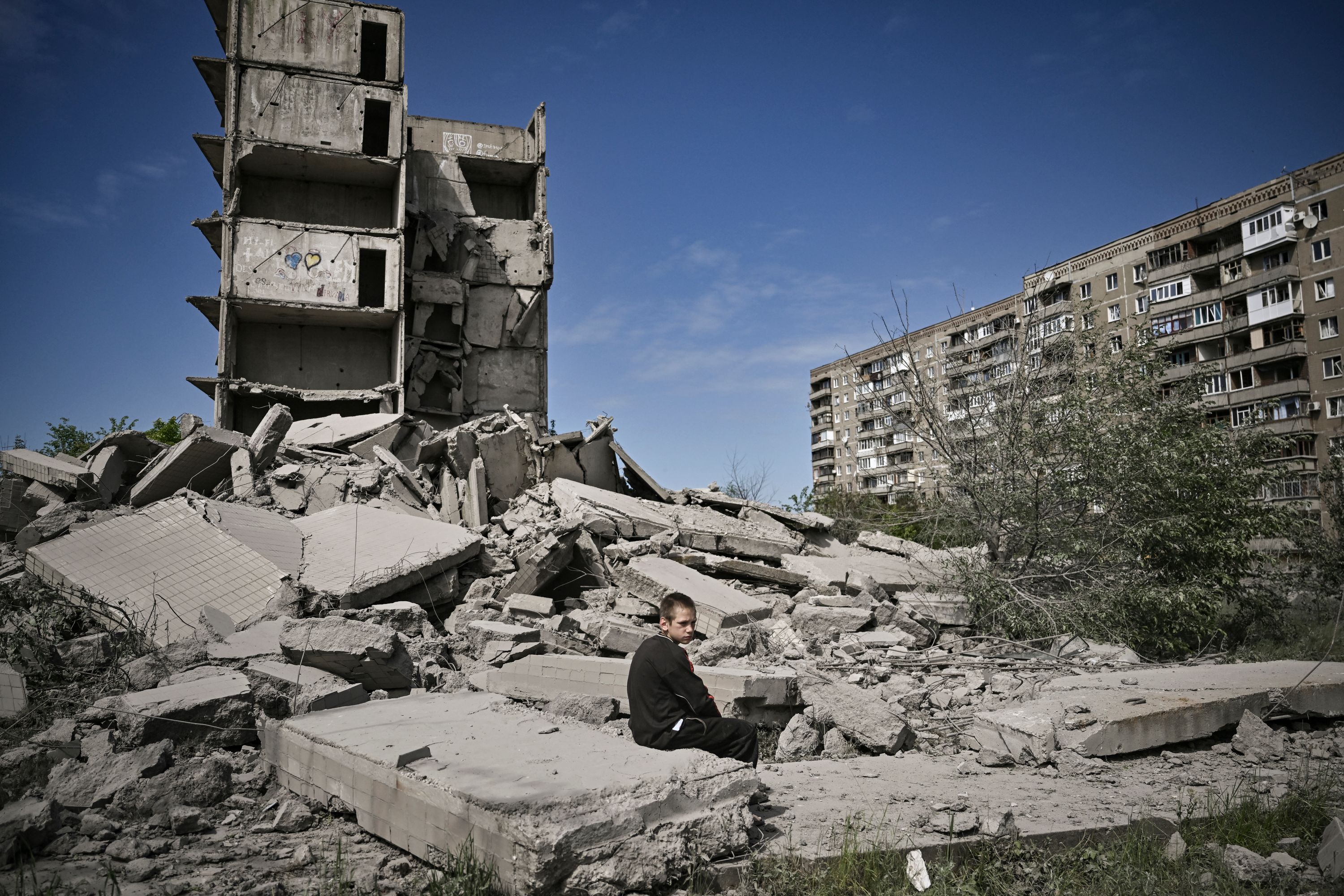 A boy sits amid shelled buildings in Kramatorsk in the eastern Ukranian region of Donbas