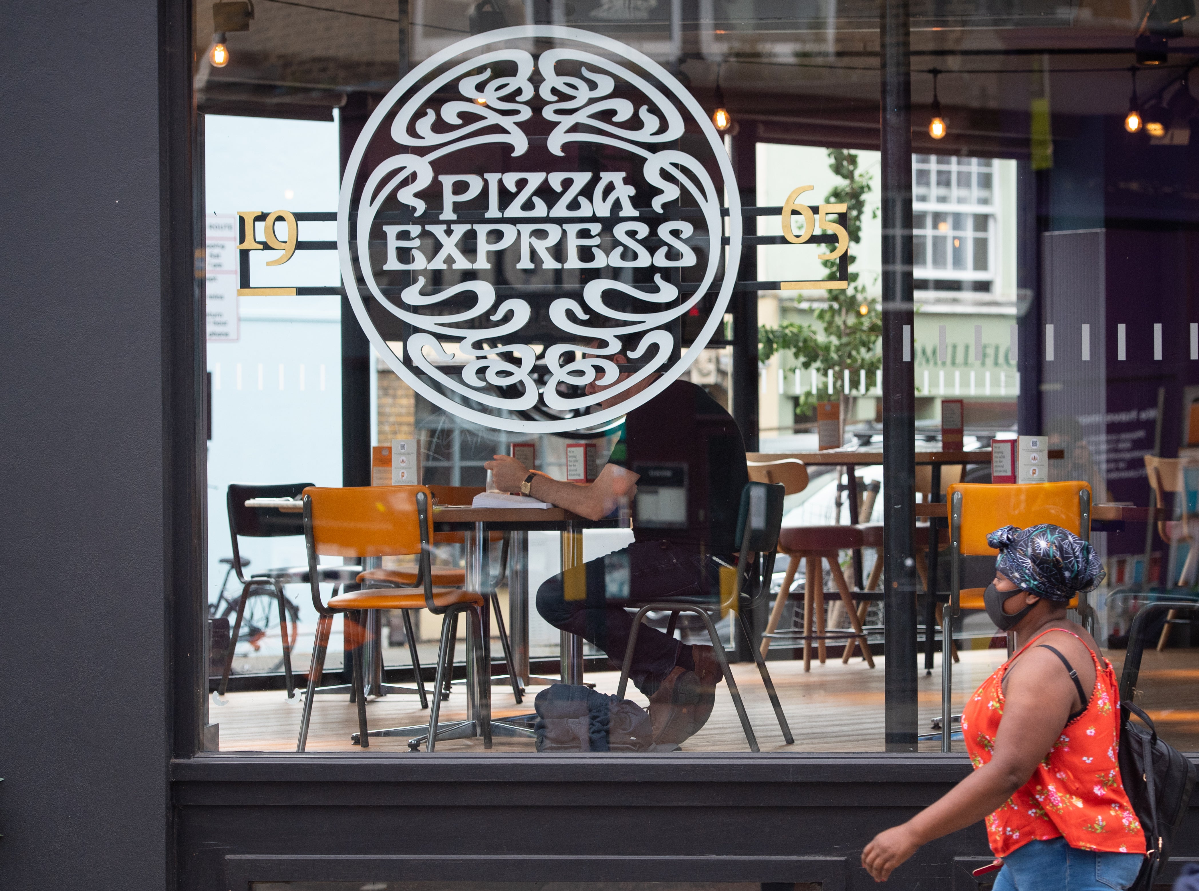 A woman passes a branch of Pizza Express in London