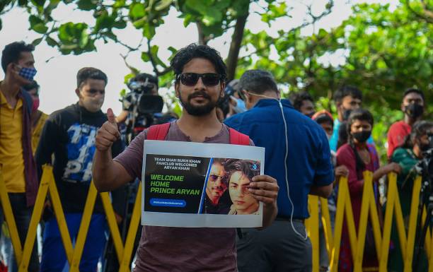 File photo: Fans stand with posters of Bollywood actor Shah Rukh Khan and his son Aryan Khan outside his residence on 29 October