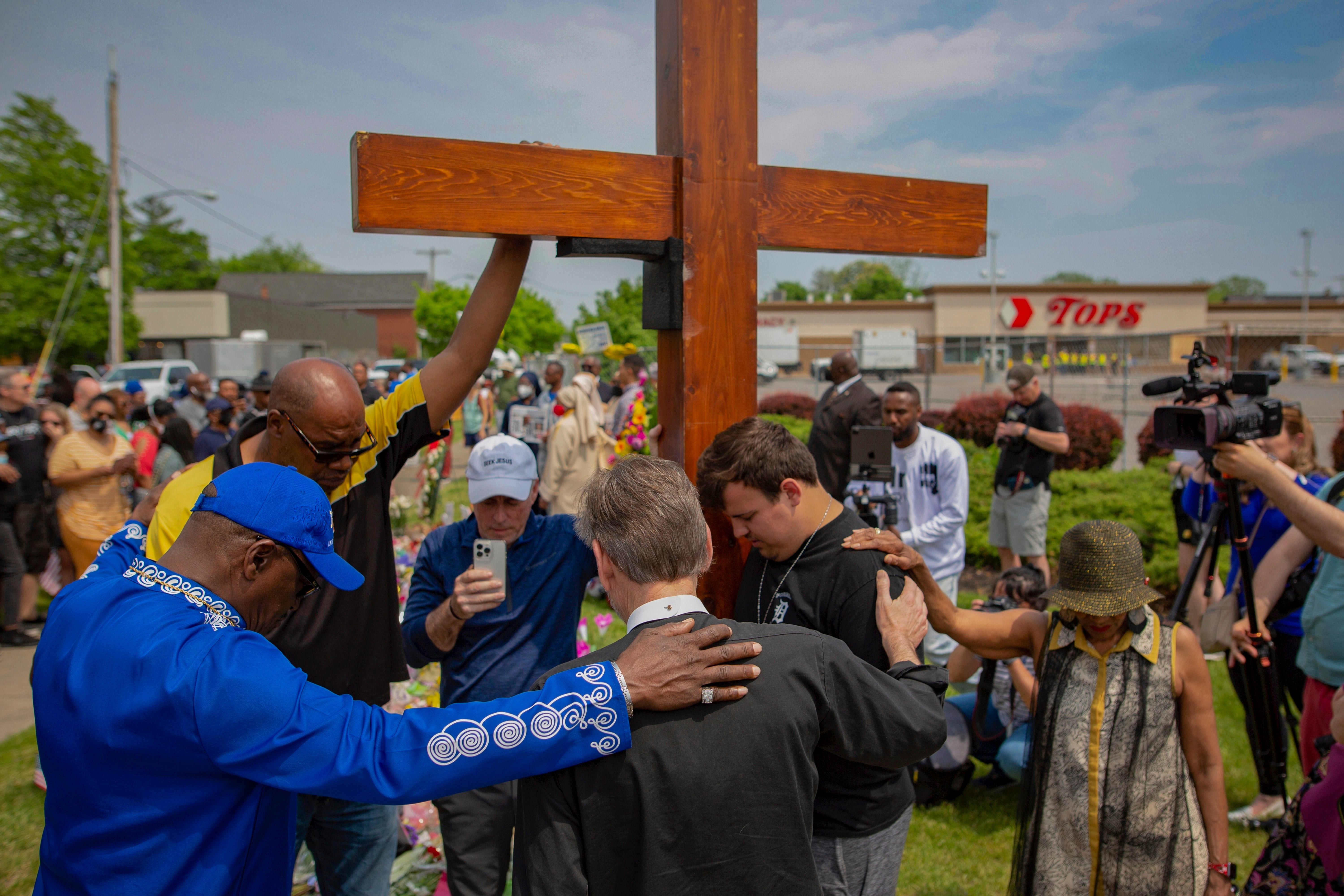 Community members pray at a memorial site for the victims of the Buffalo mass shooting