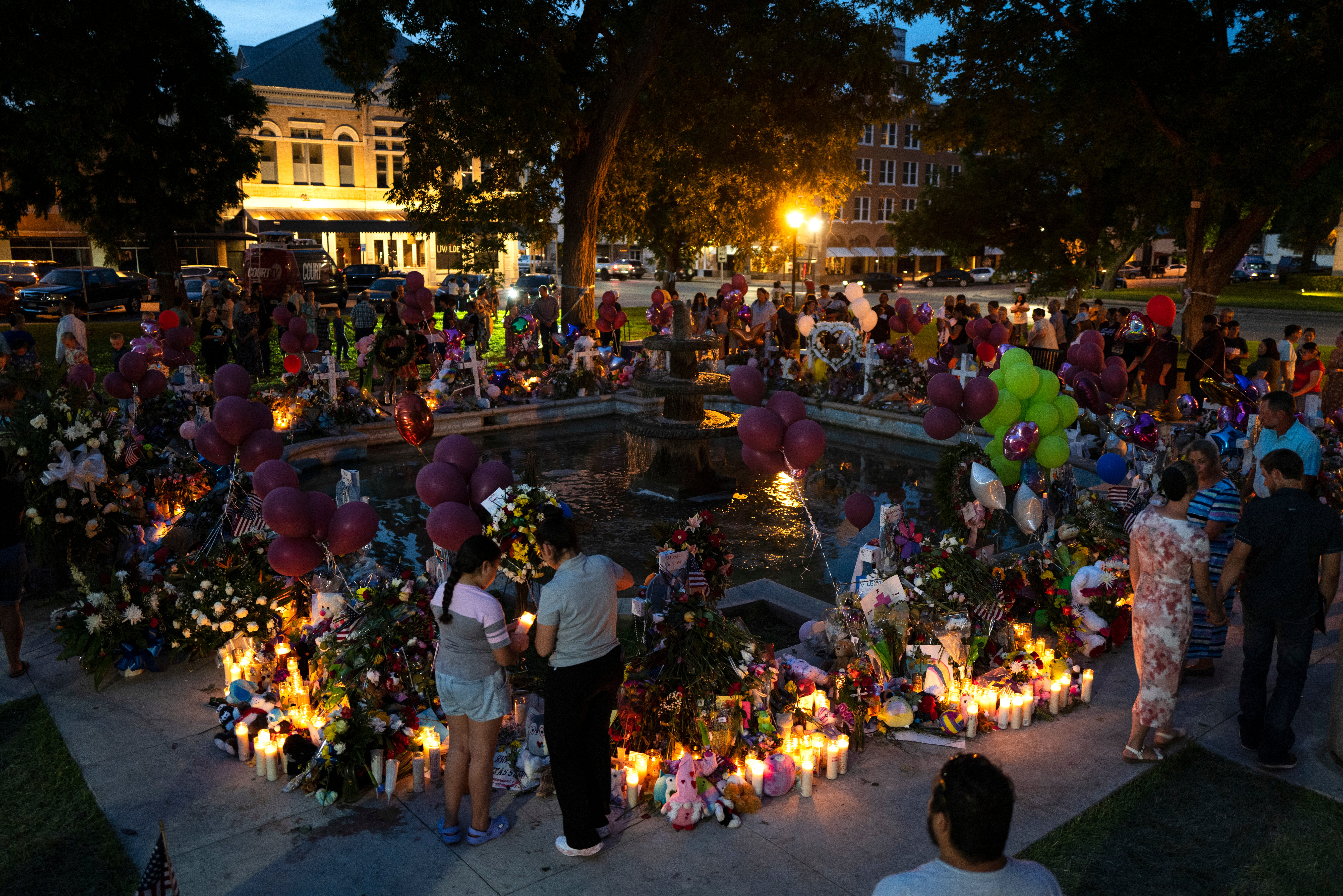 People visit a memorial set up in a town square to honor the victims killed in the elementary school shooting earlier in the week in Uvalde, Texas, late Saturday, May 28, 2022.