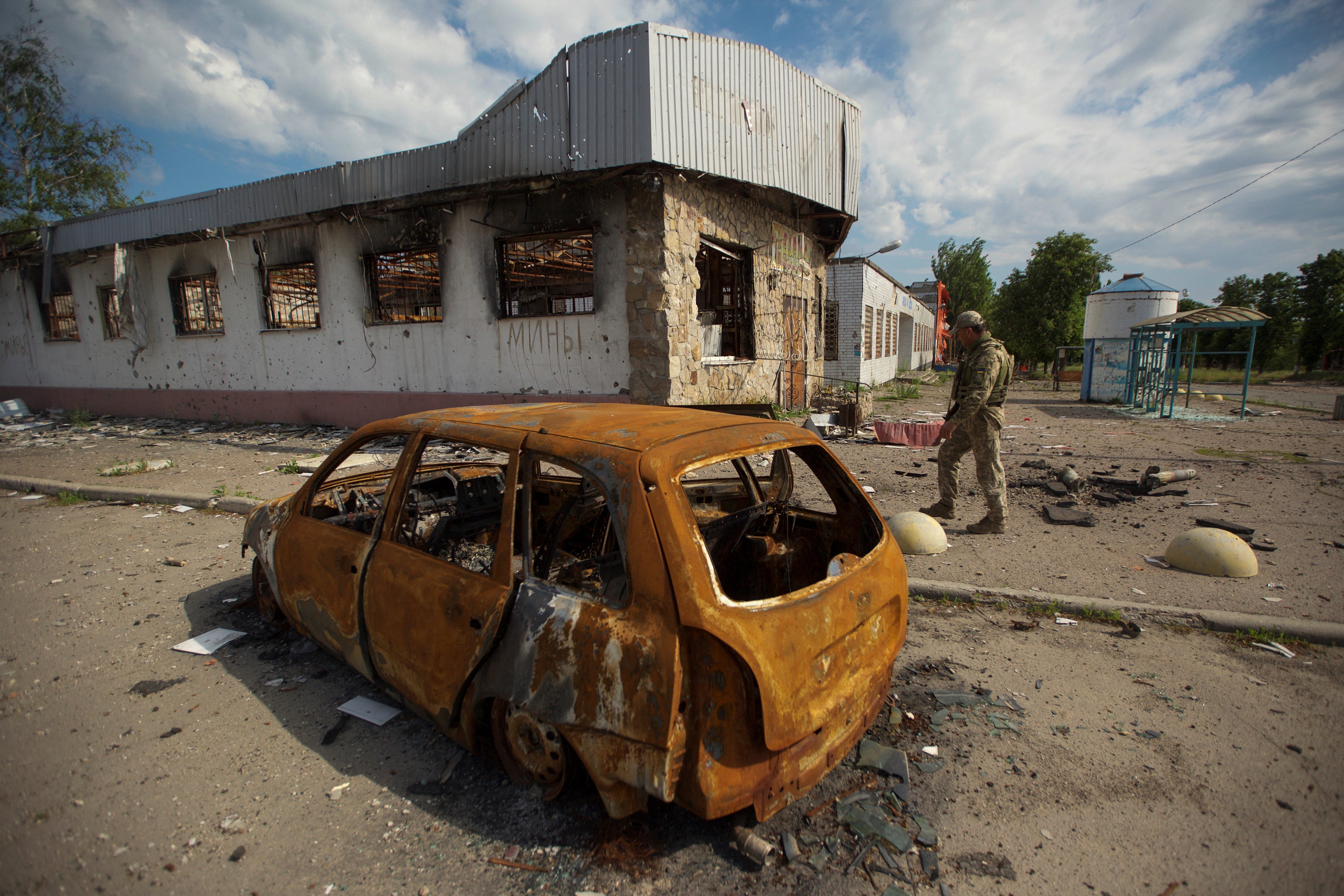 A Ukrainian serviceman inspects an area damaged by a Russian military strike, as Russia's attack on Ukraine continues