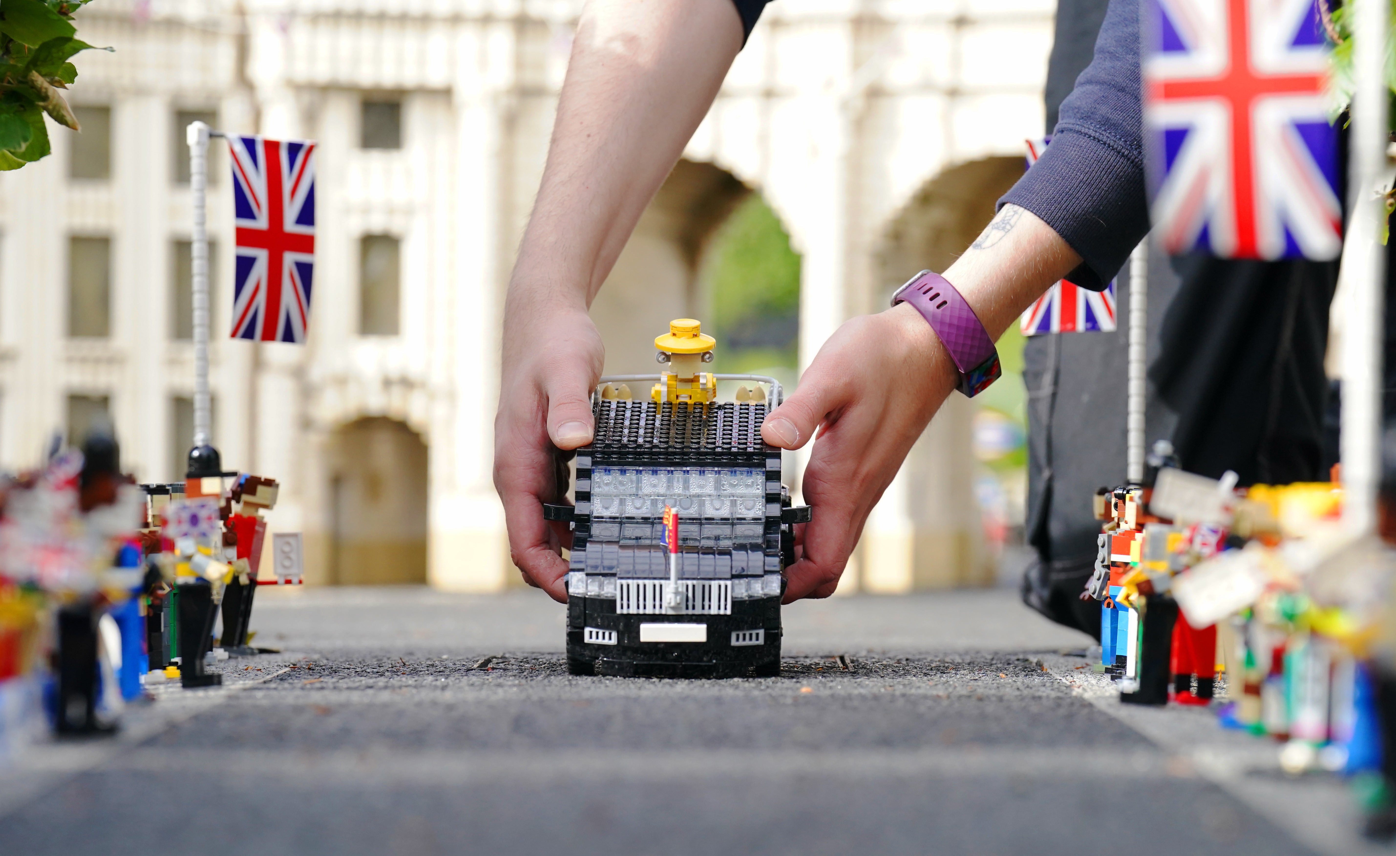 Model maker Freya Groom places a replica of the Queen in an animated vehicle in the display (Jonathan Brady/PA)