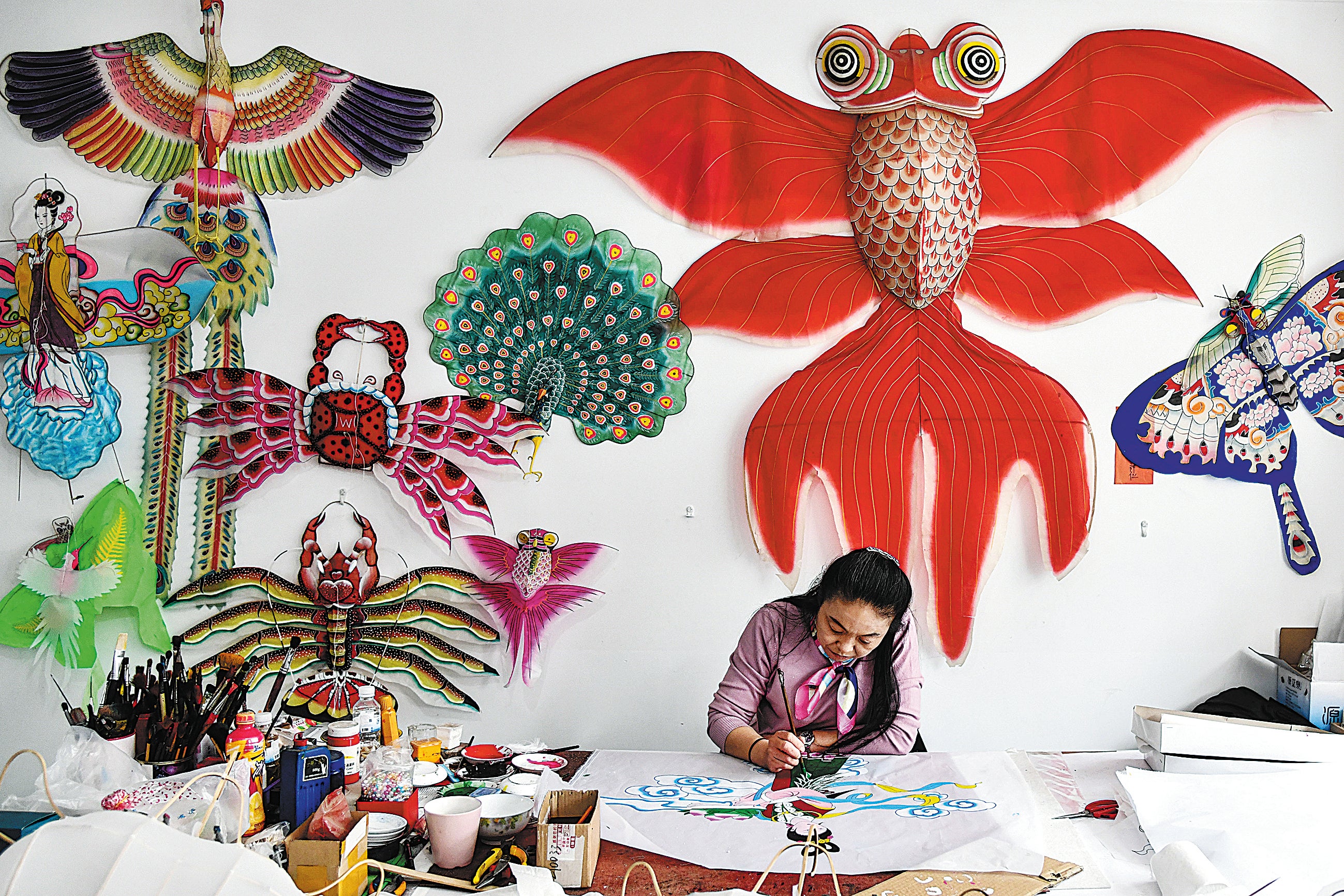 Yang Hongwei, an intangible cultural heritage inheritor of Weifang kite-making in Yangjiabu village, Weifang, Shandong province, paints a kite in April 2021