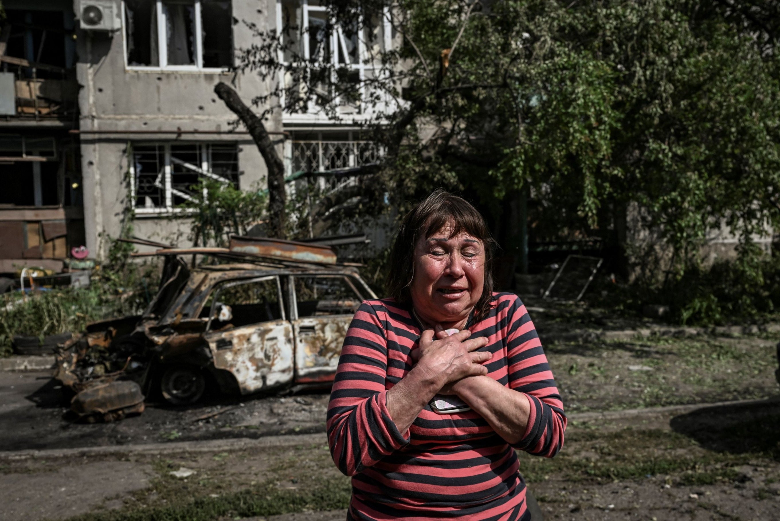 A woman reacts outside an apartment block destroyed by Russian missiles