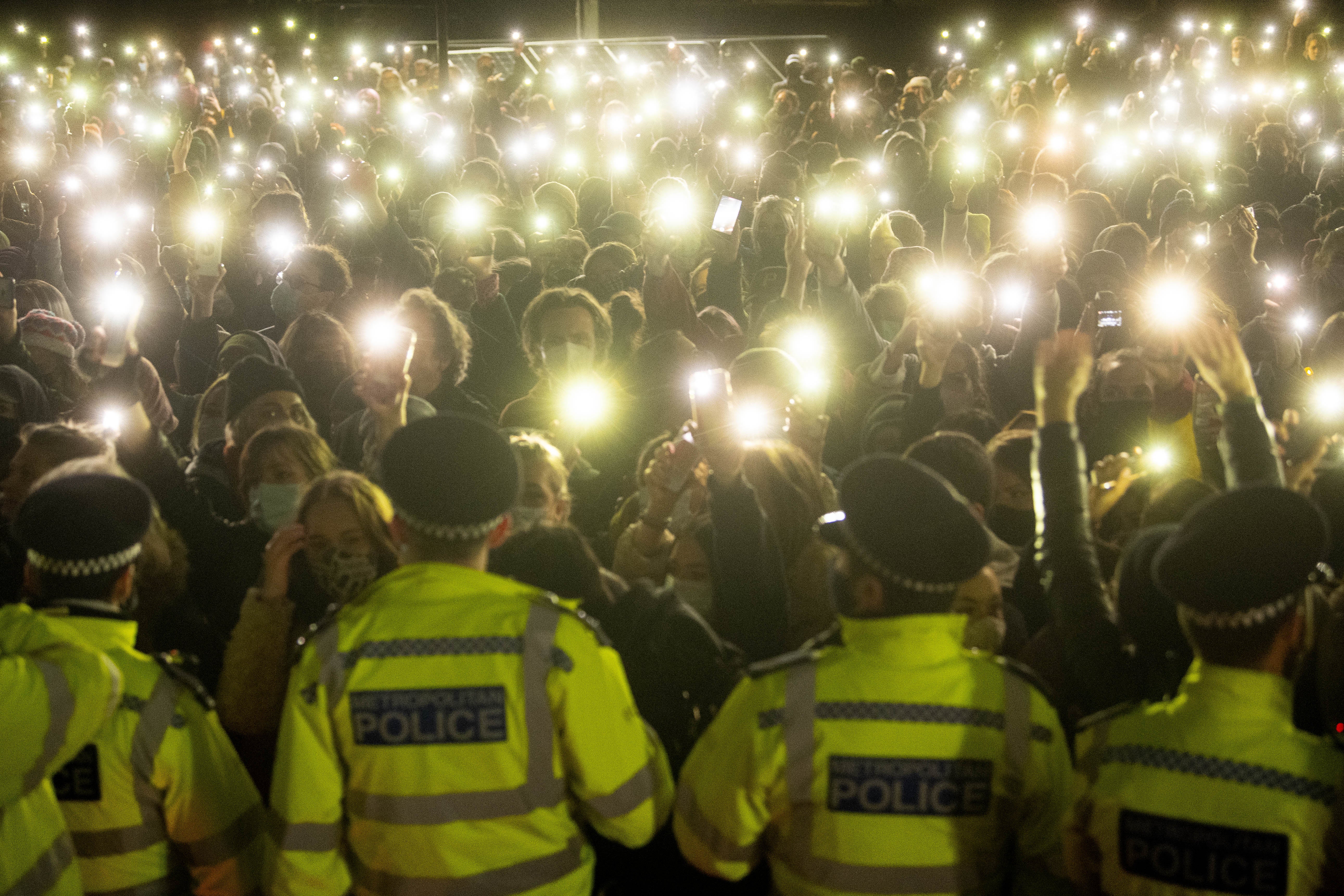 People in the crowd turn on their phone torches in Clapham Common, London, for a vigil for Sarah Everard, on 13 March 2021