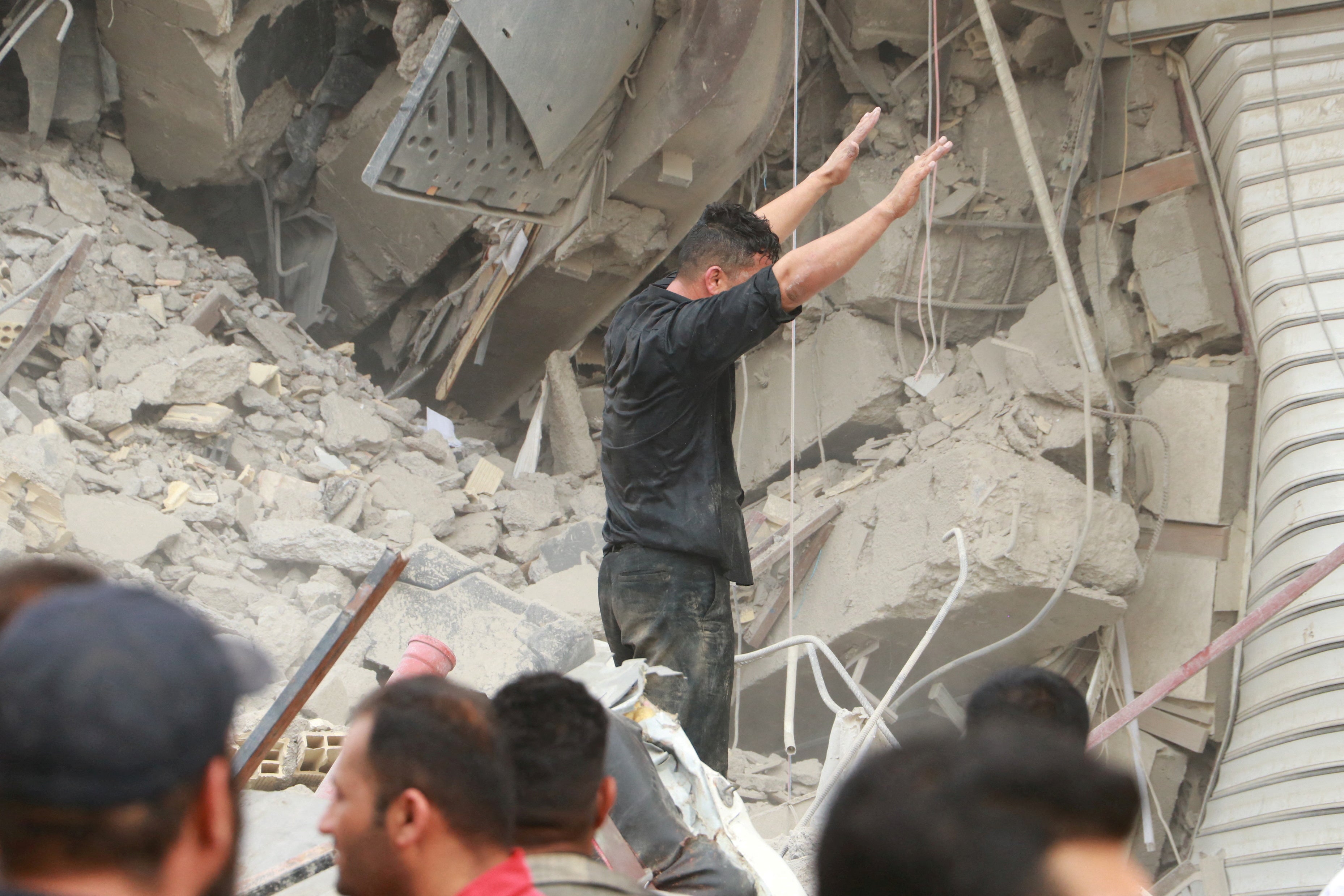 Iranians gather as rescue crews work at the site of the collapsed building