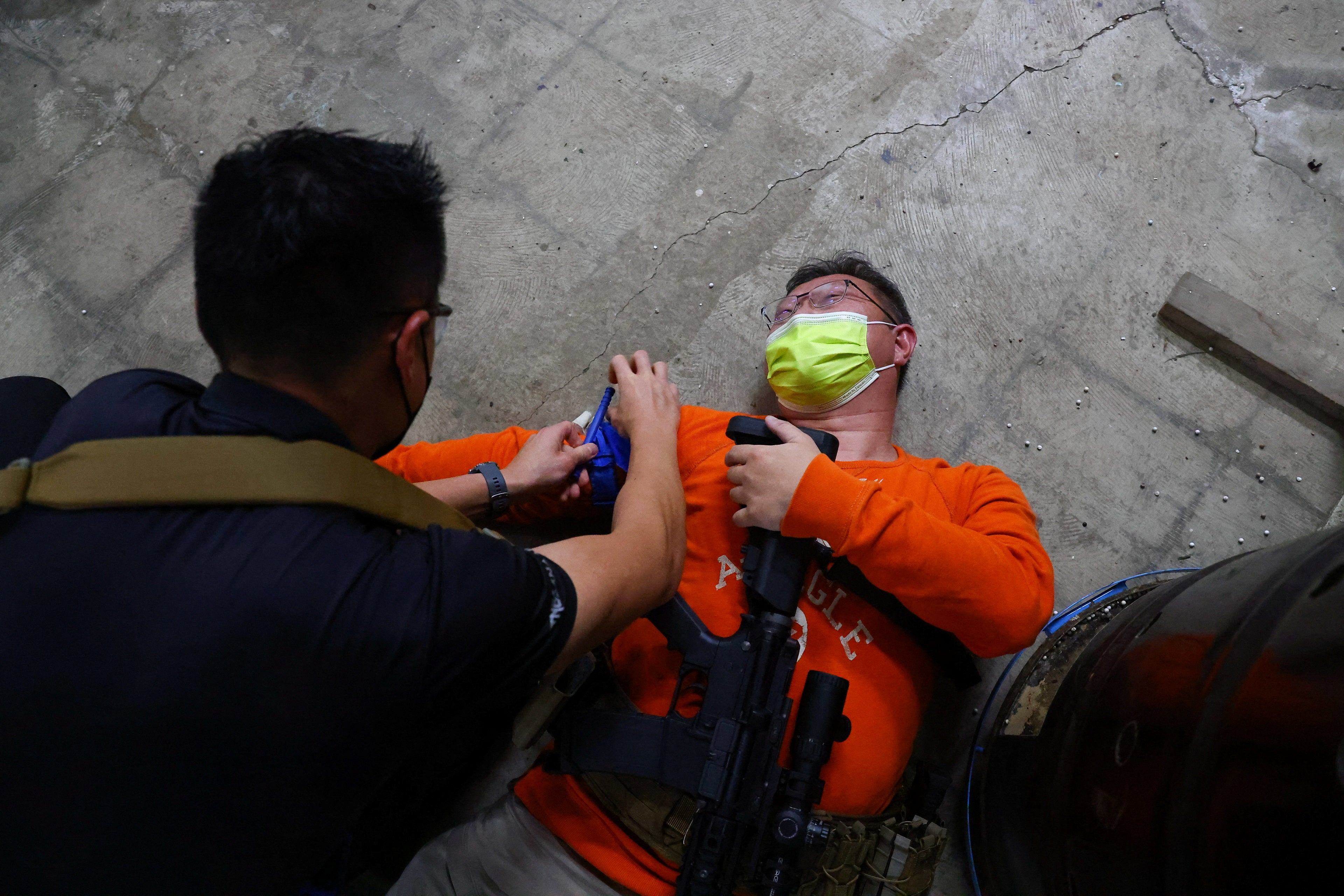 A trainee pretends to be injured while others perform first aid on him