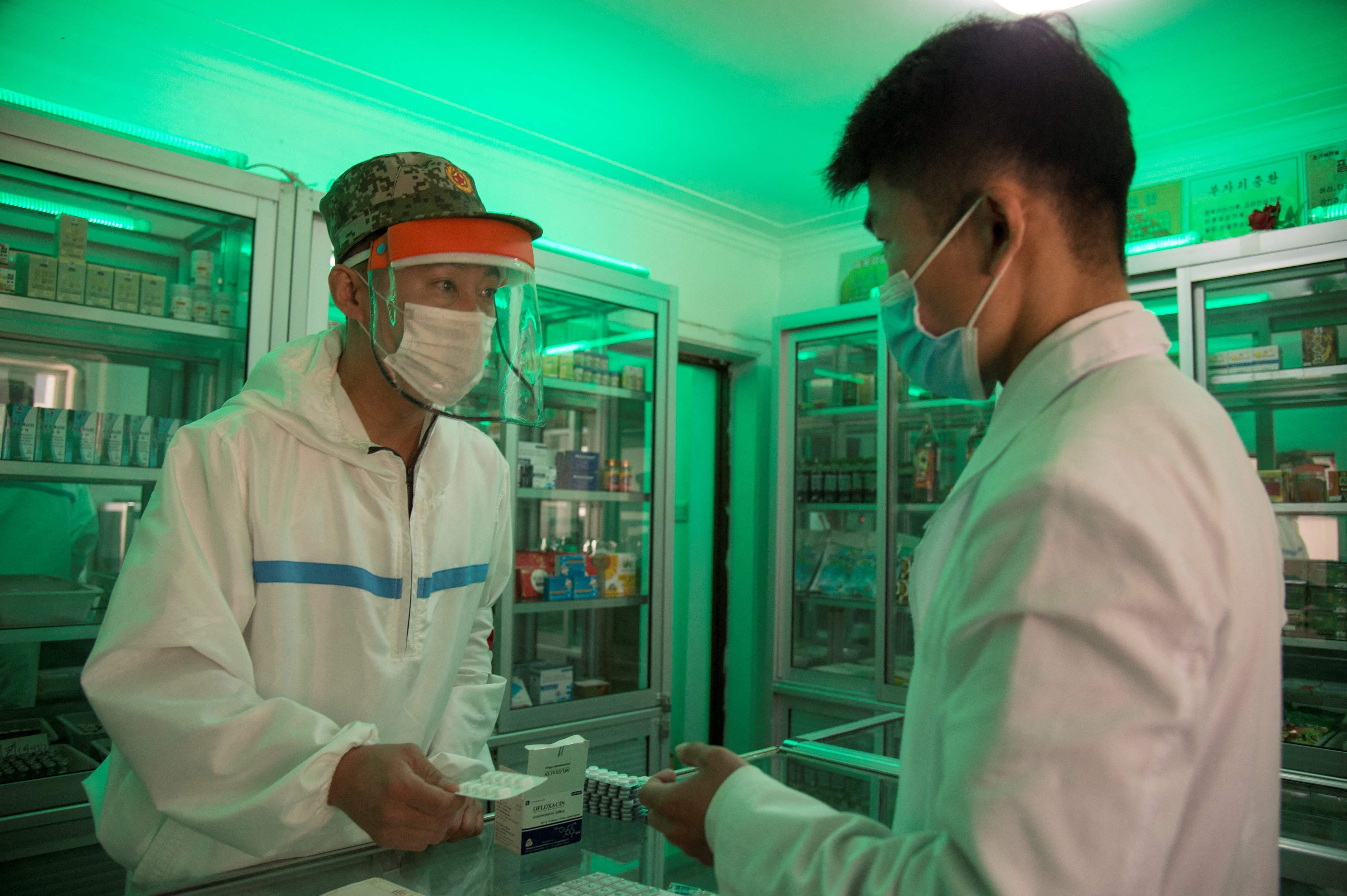 A doctor from the Korean People’s Army visits a pharmacy to give a man prescription medicine in Pyongyang