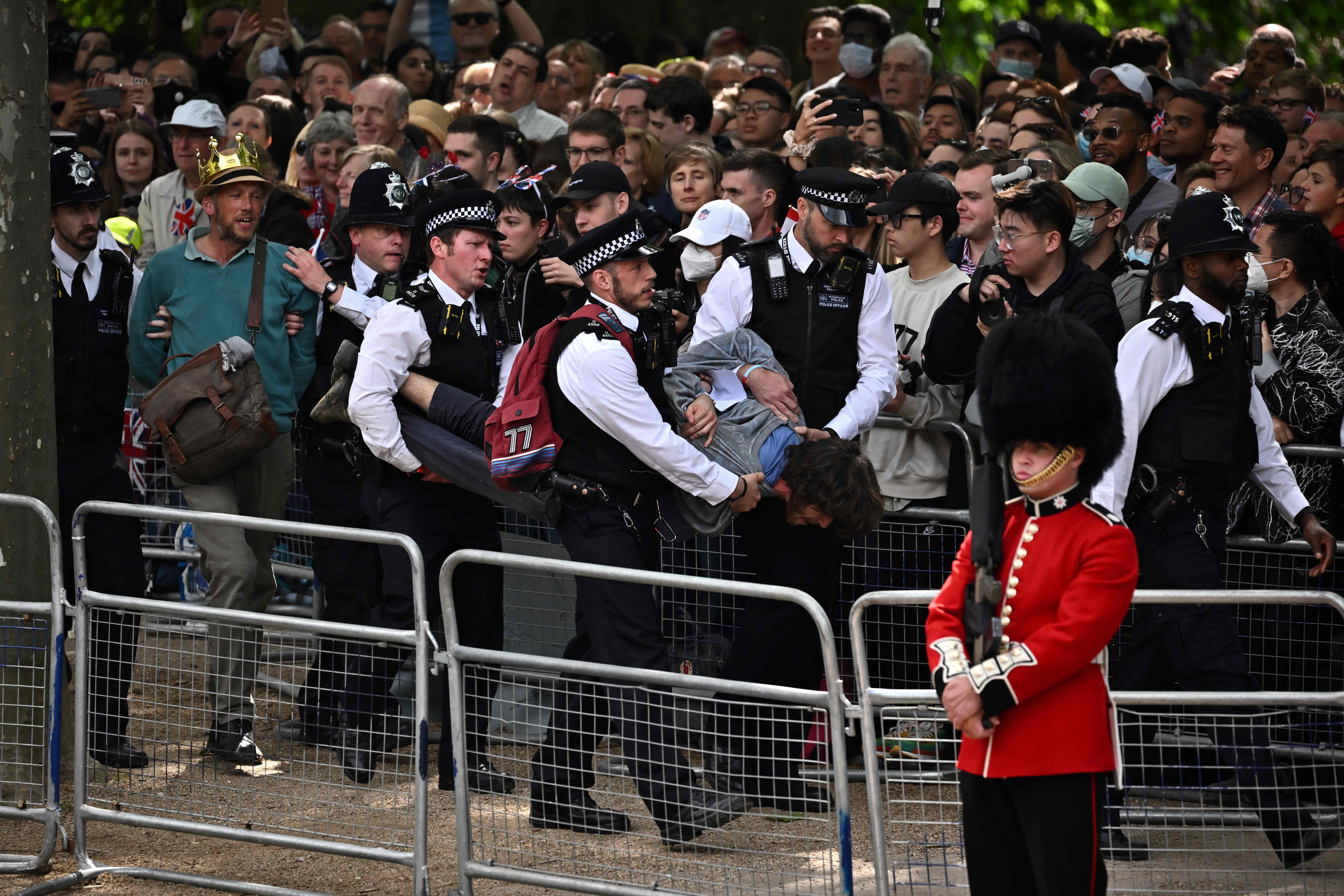 Police escort protesters away from the Mall during the Queen's Birthday Parade