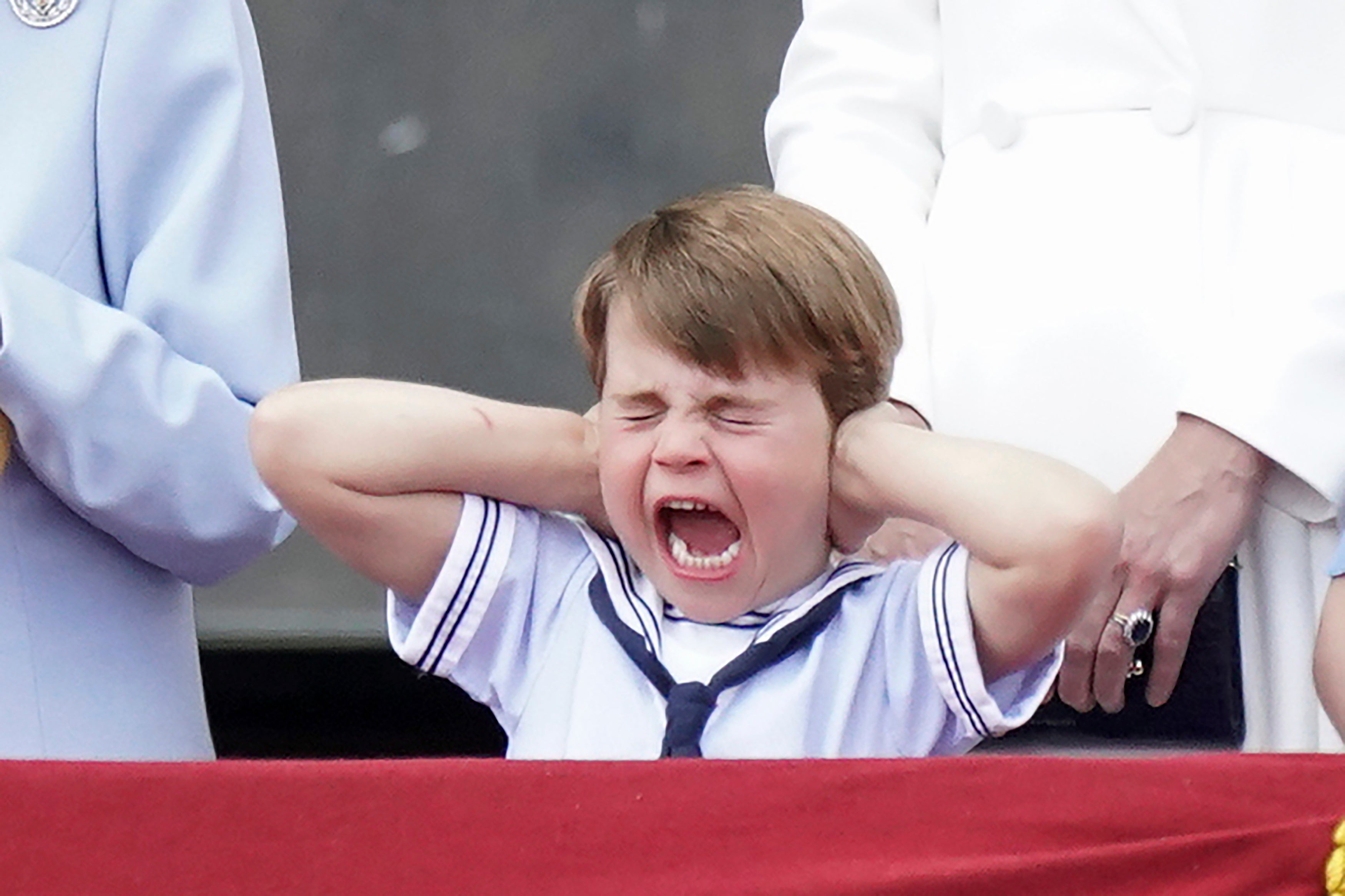 Prince Louis covers his ears from the balcony of Buckingham Place