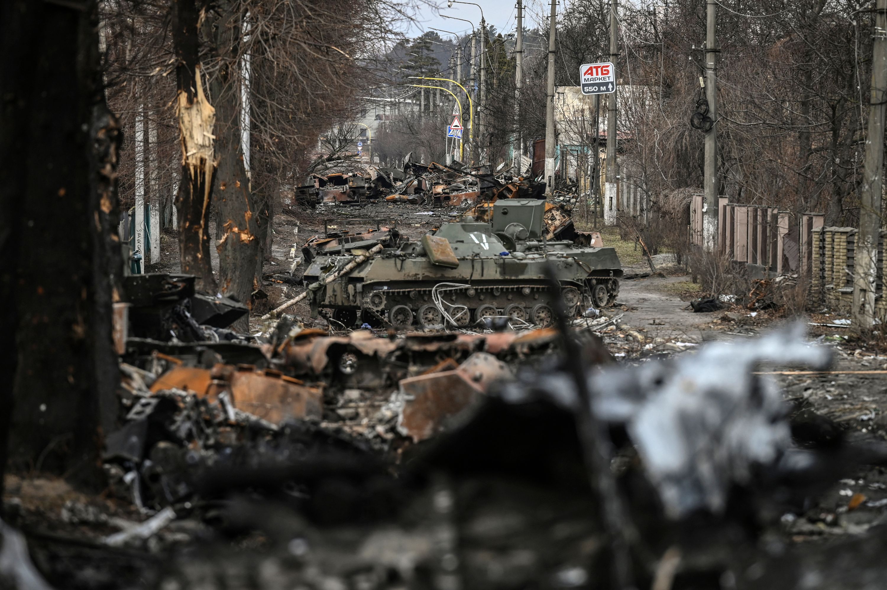 A woman navigates a debris-filled Bucha street in April