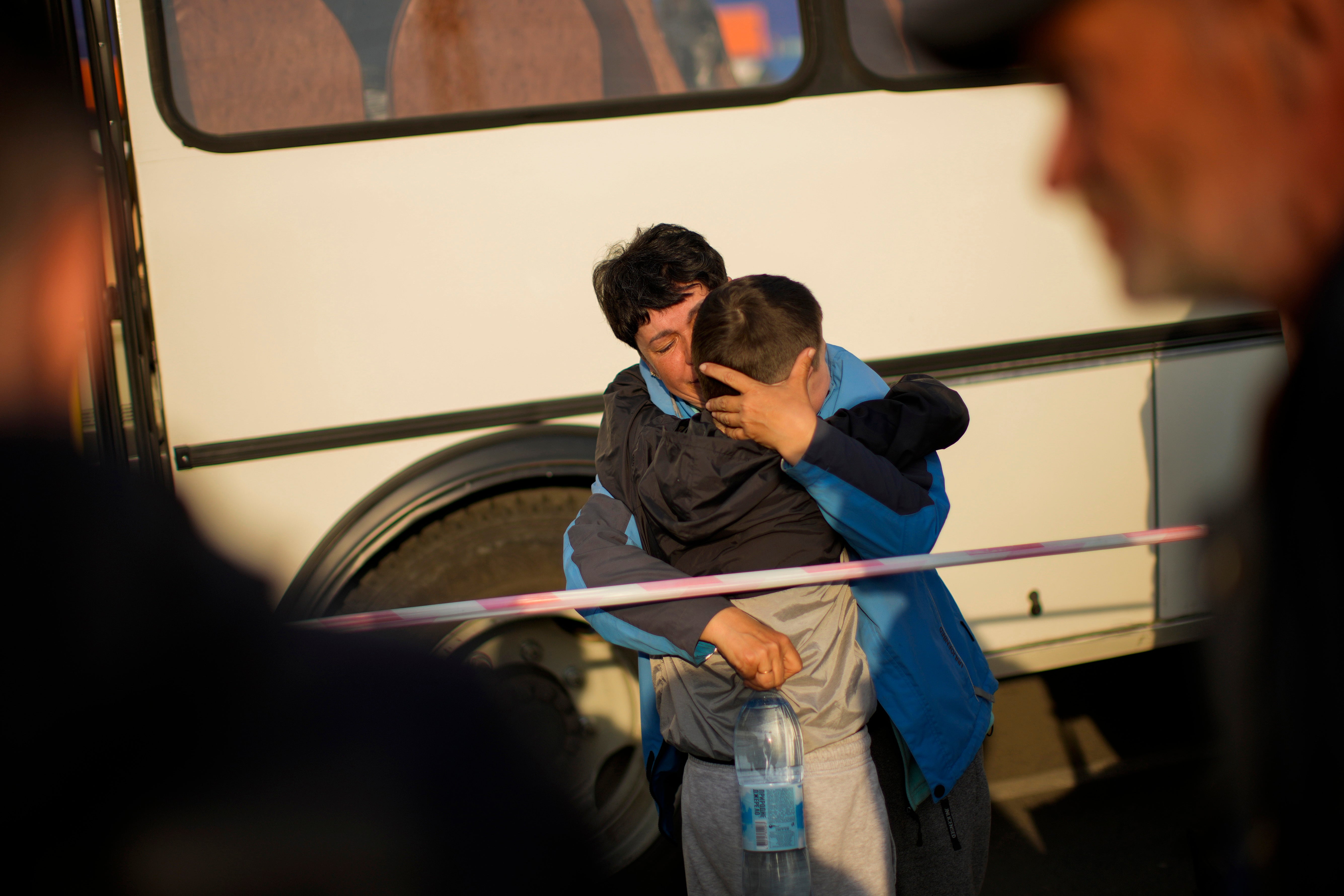 A woman hugs her grandson as she arrives in a bus with people who fled to a reception centre for displaced people in Zaporizhzhia