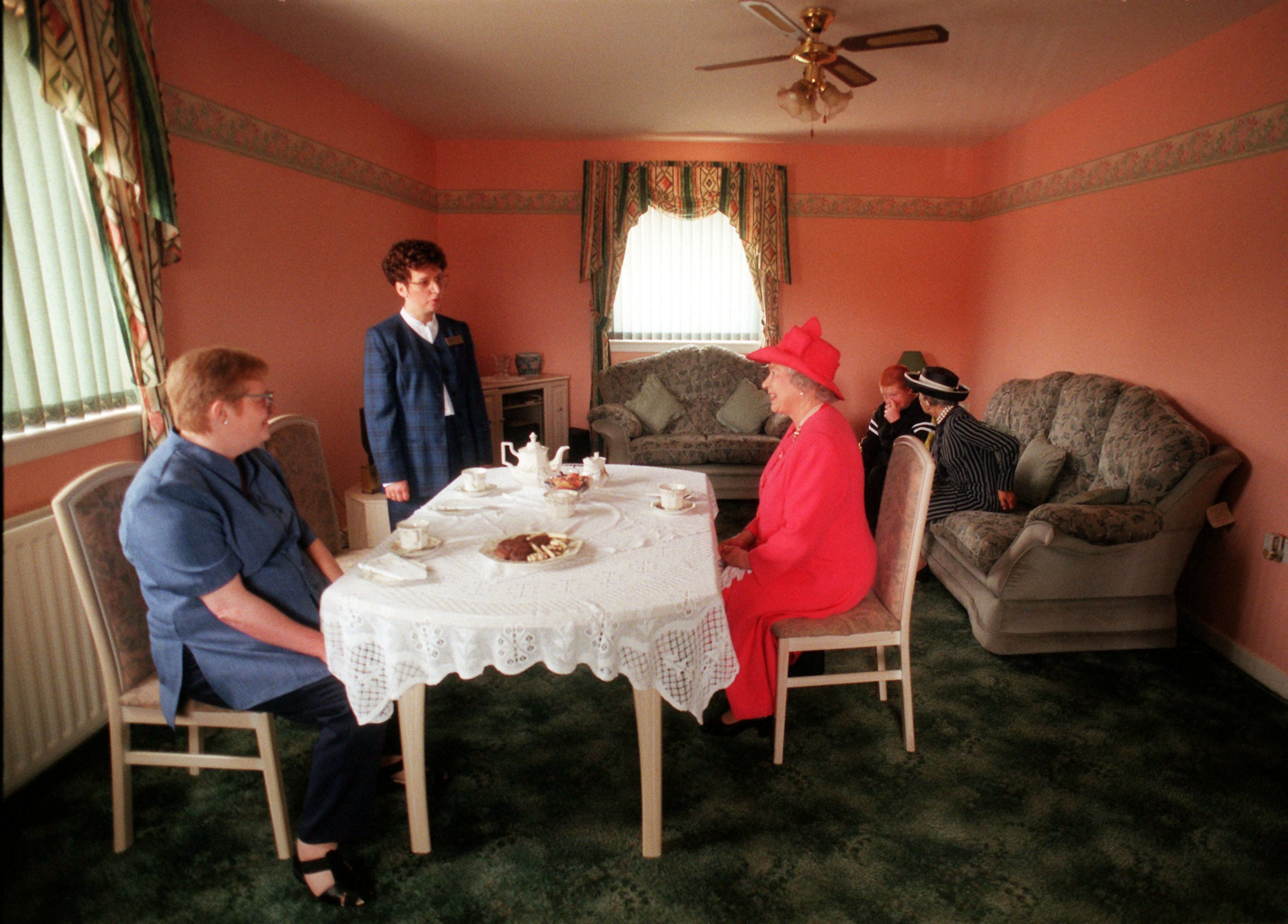 The Queen joins Susan McCarron, her 10-year-old son James and housing manager Liz McGinniss for tea in the Castlemilk area of Glasgow in July 1999