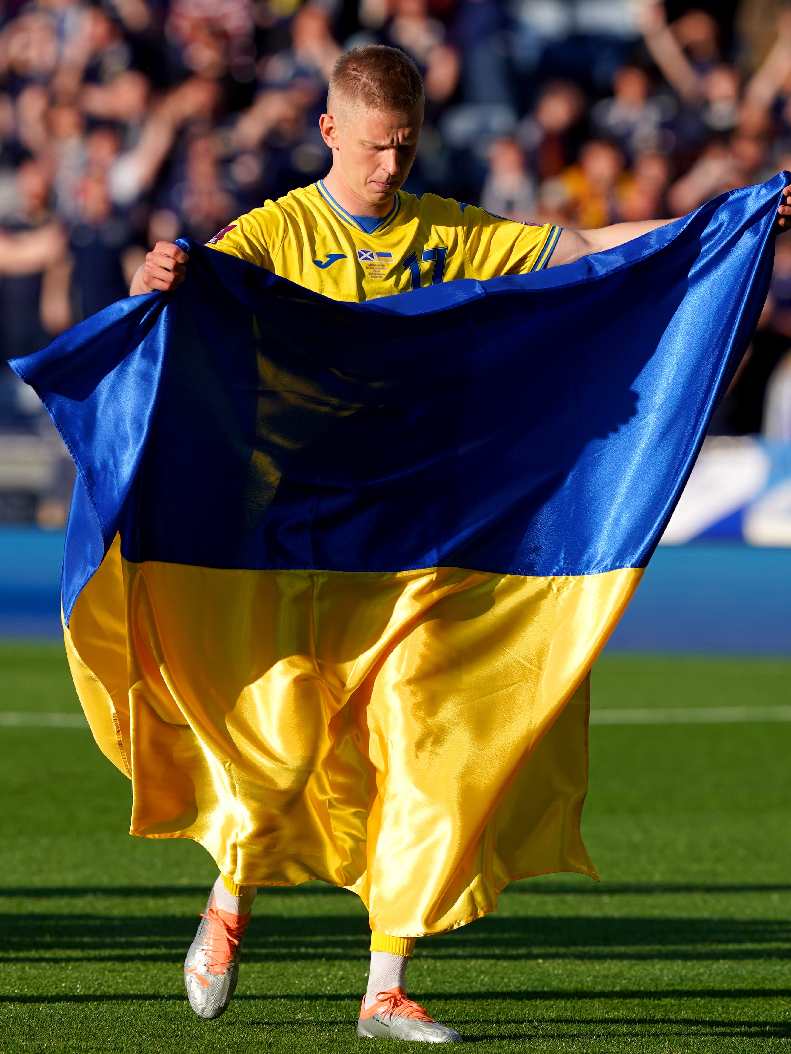 Oleksandr Zinchenko holds up the Ukraine flag on the pitch ahead of his team’s victory over Scotland (Andrew Milligan/PA)